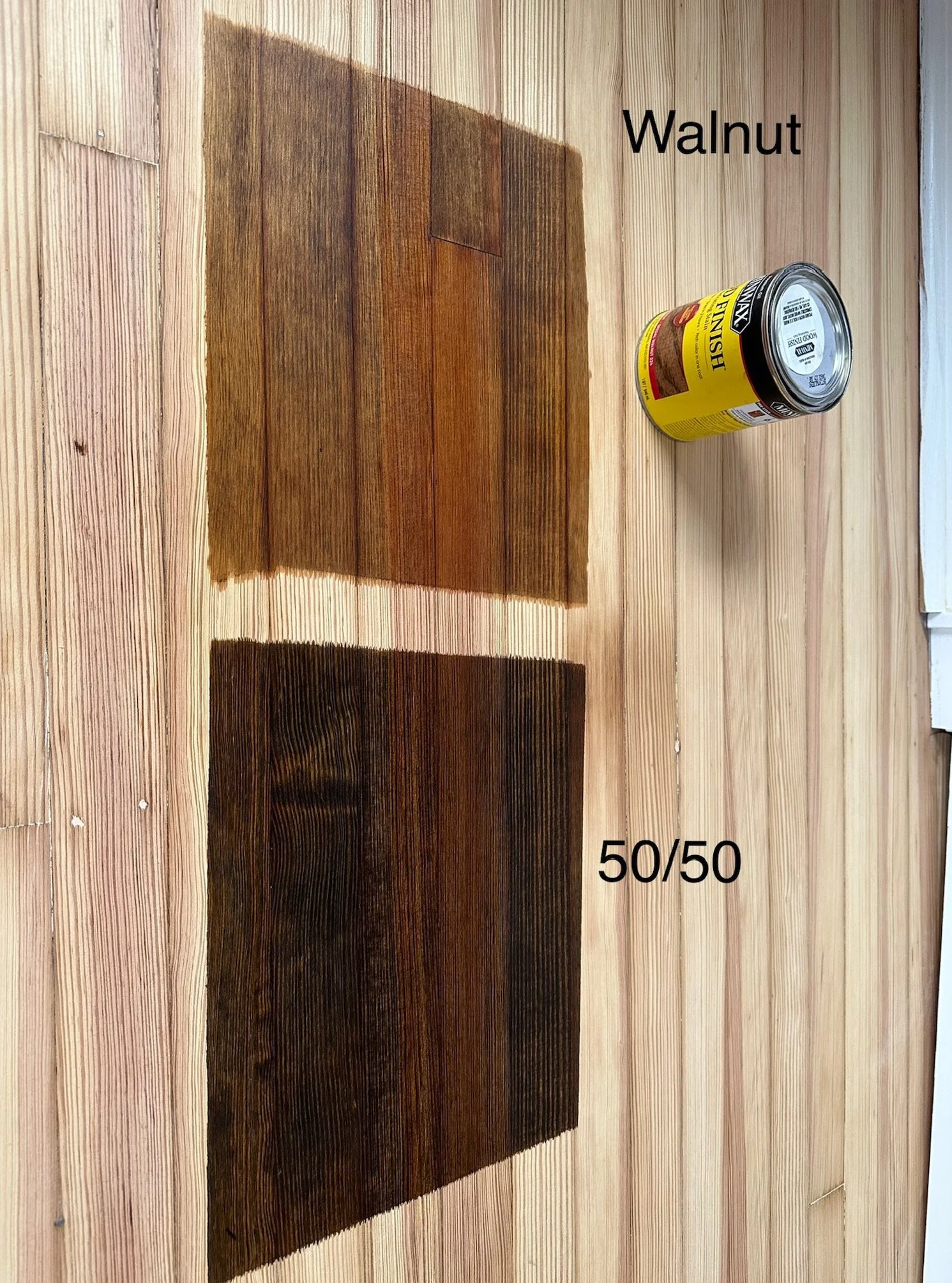 Comparison of two wood stain samples on a wooden surface, labeled Walnut and 50/50, with a can of stain placed nearby