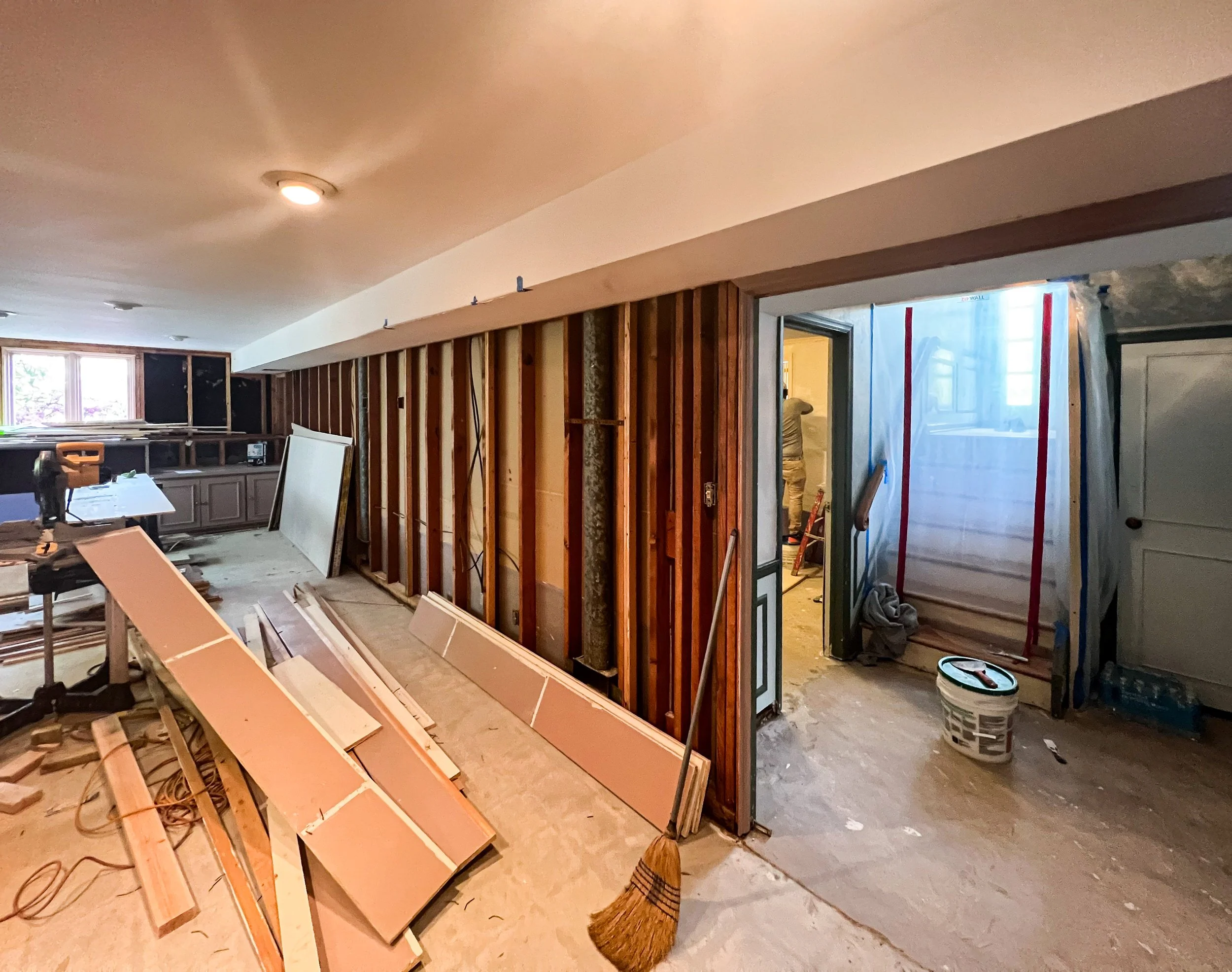 Interior of a house under renovation with drywall and wood framing, construction tools, and materials scattered around.