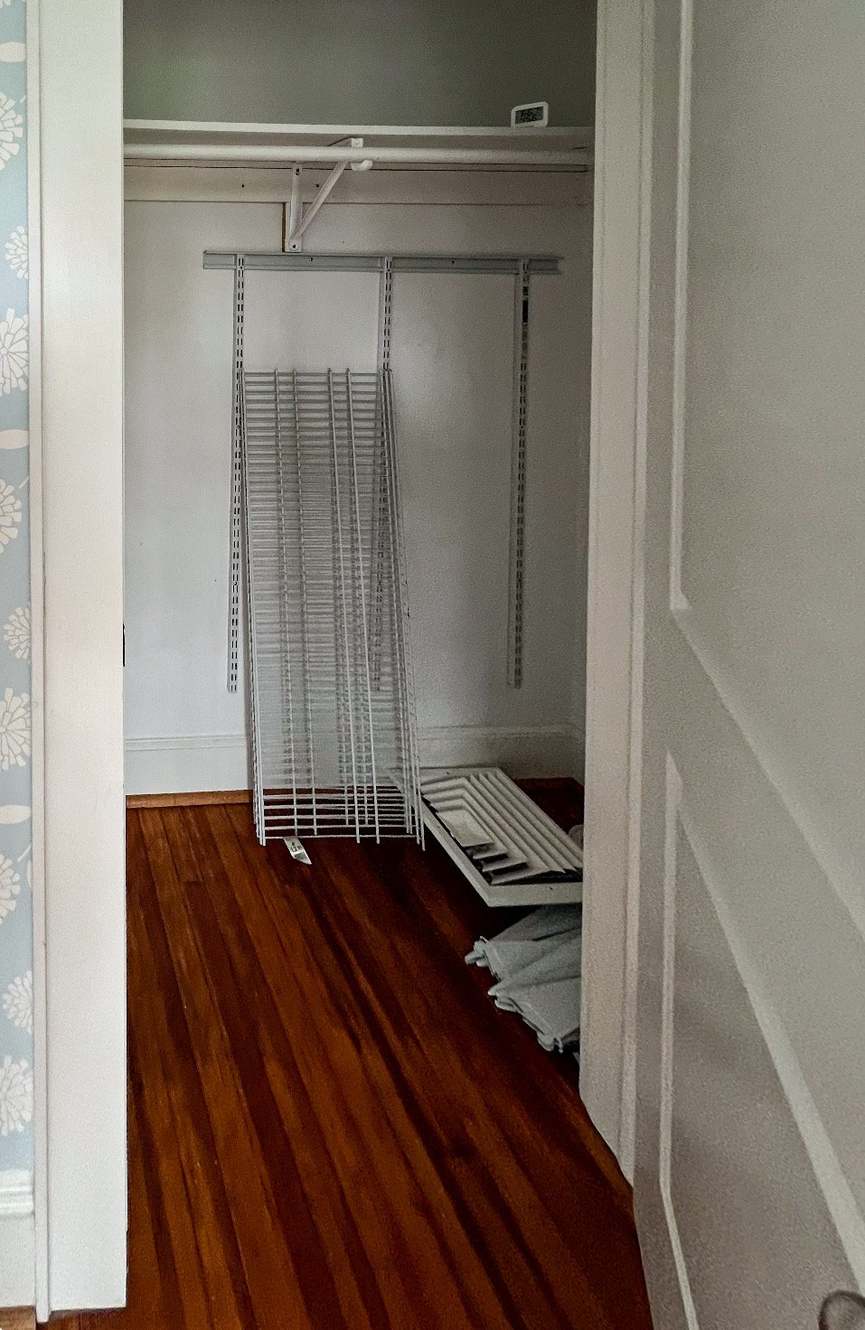 Empty closet with metal shelving and floor panels on the ground.