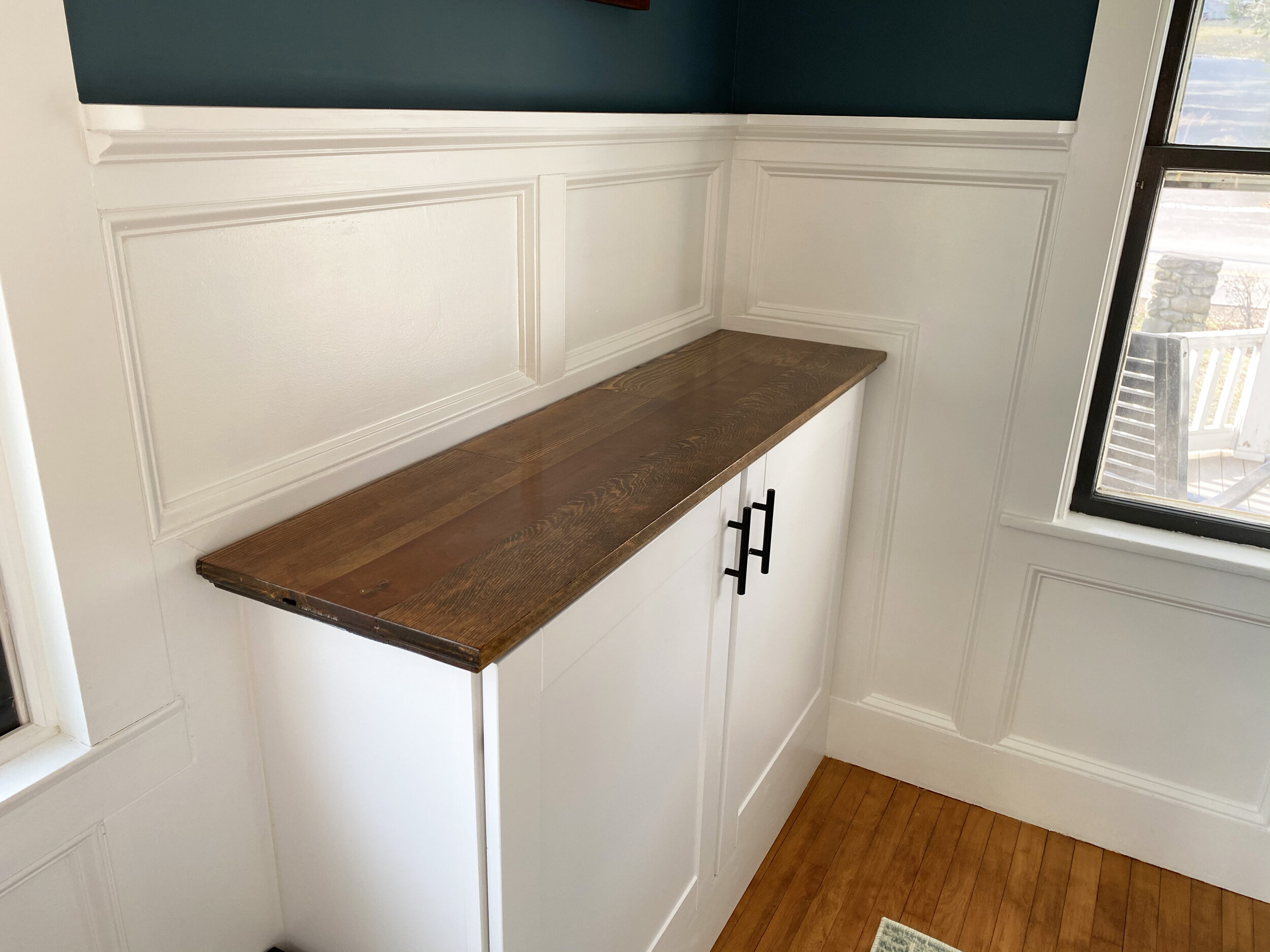 Custom wainscoting, cabinets, and a cabinet top created using an antique door belonging to the client