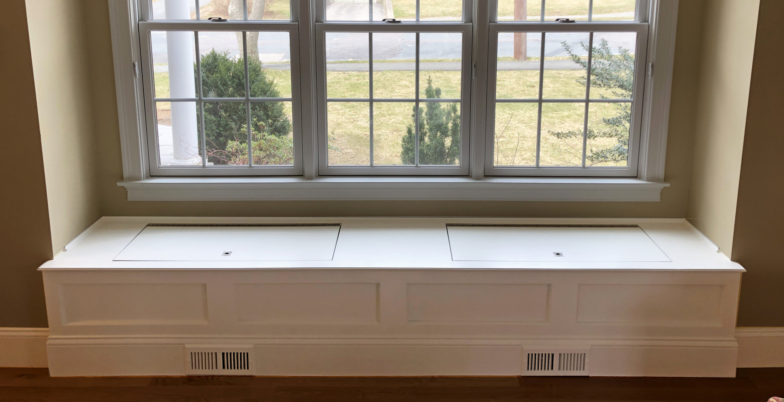 A window seat with integrated HVAC vents in the baseboard