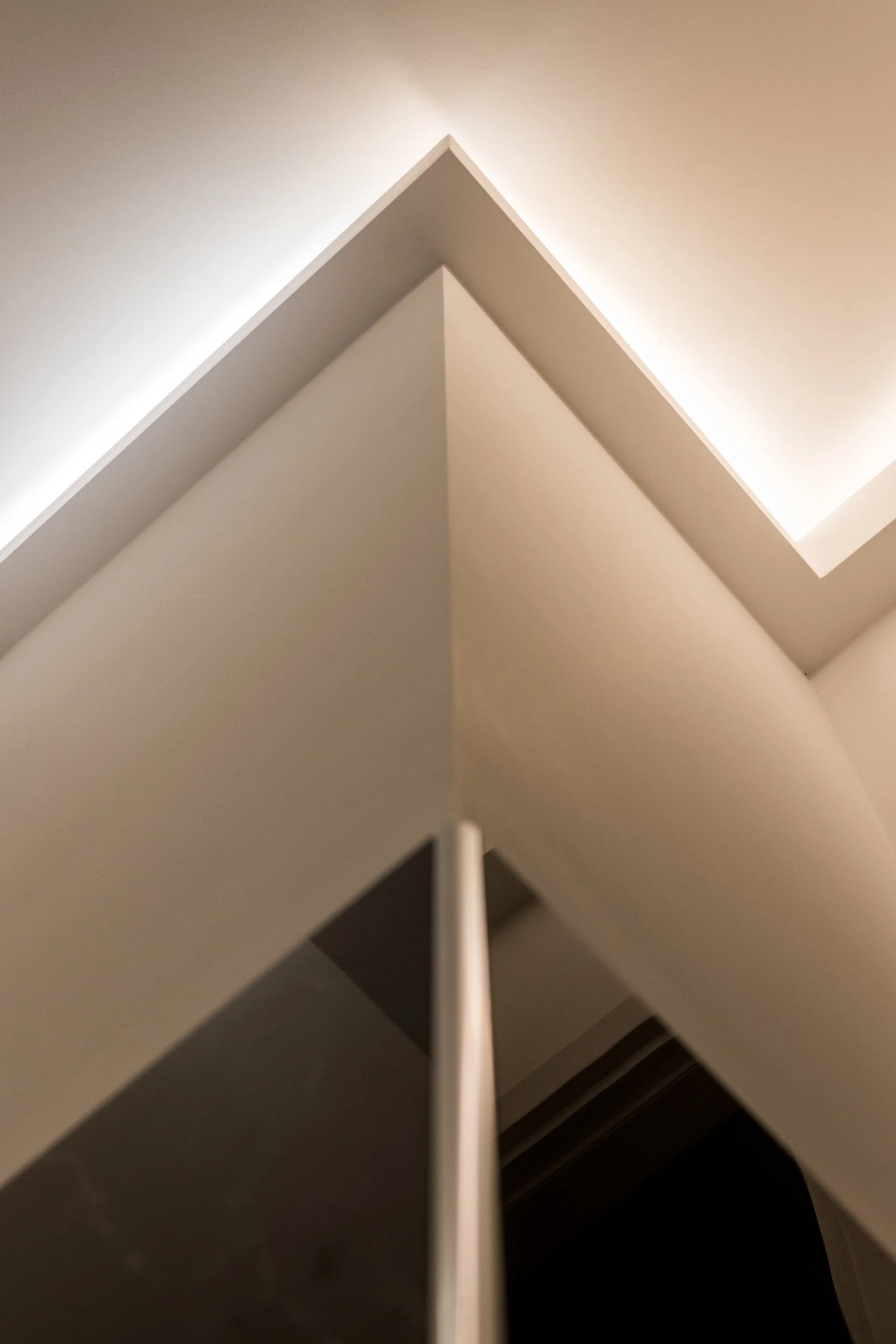La veletta retroilluminata. Nel progetto Dinamo a Palermo, la continuità tra falegnameria, pareti e soffitto costruisce una sequenza dinamica di attraversamenti e prospettive. La luce indiretta enfatizza il segno della curva e contribuisce alla defin