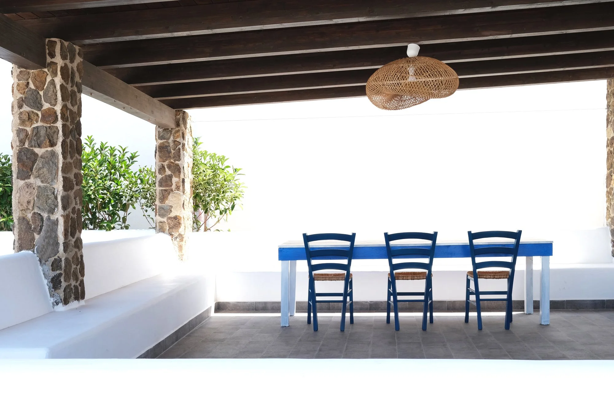 Pergola con pilastri in pietra vulcanica e seduta integrata affacciata sul paesaggio mediterraneo di Ustica.