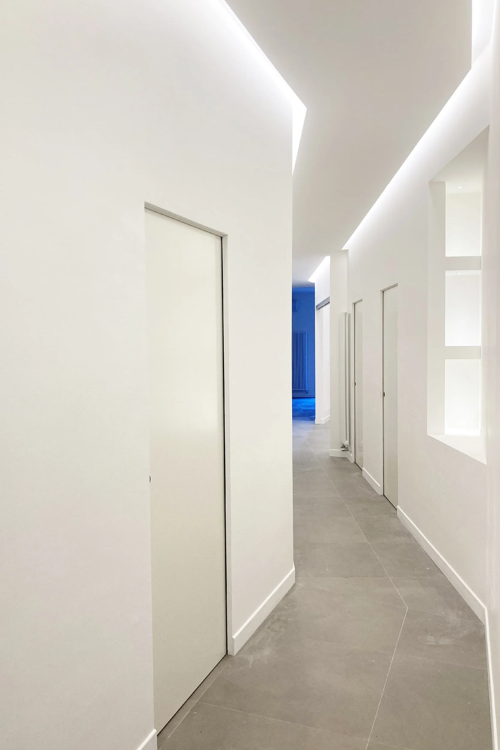 Il corridoio costituisce l'elemento generatore del progetto. Le sue geometrie oblique costruiscono una sequenza prospettica che accompagna lo sguardo dall'ingresso verso la zona giorno, trasformando il percorso distributivo in esperienza architettoni