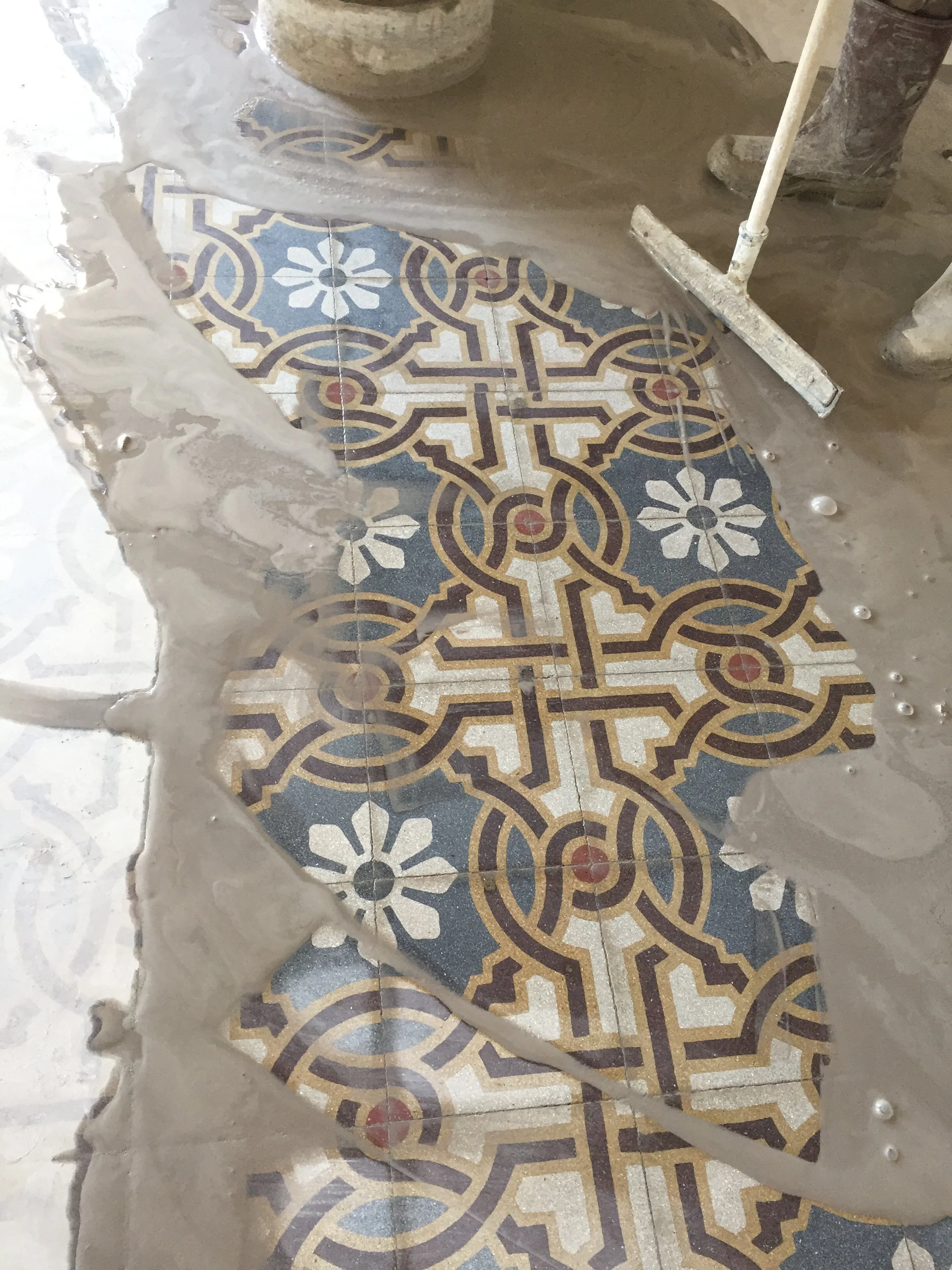 Fase di restauro e lucidatura delle cementine storiche in un appartamento d'epoca a Palermo. L'immagine mostra il recupero del pavimento originale attraverso operazioni di pulitura, levigatura e valorizzazione delle superfici decorative. Il restauro 