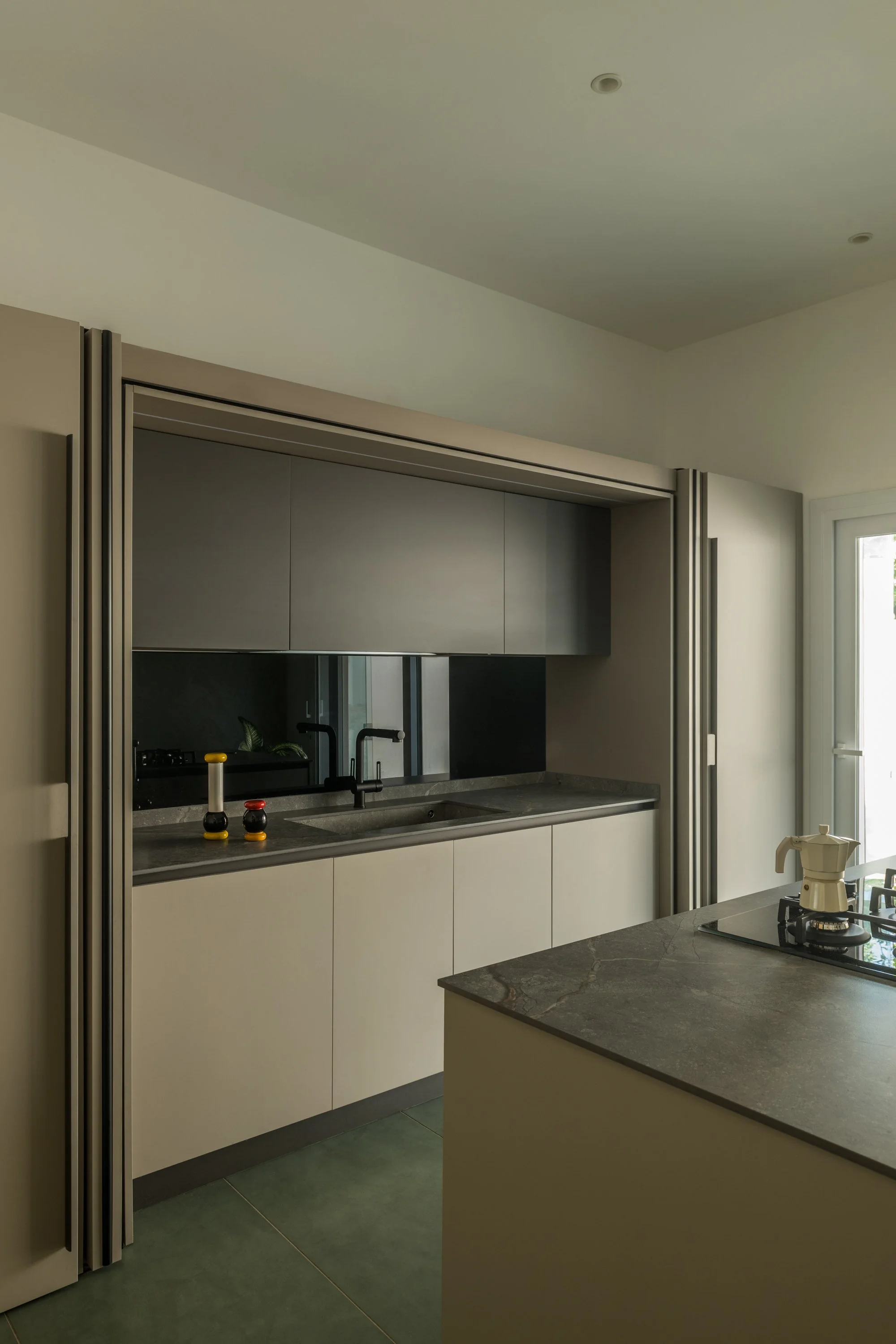 Cucina della villa di Mondello, Palermo, nella configurazione aperta del sistema contenitore. L’apertura rivela il piano operativo e le attrezzature della cucina, trasformando la parete continua in un elemento funzionale della nuova distribuzione. Il