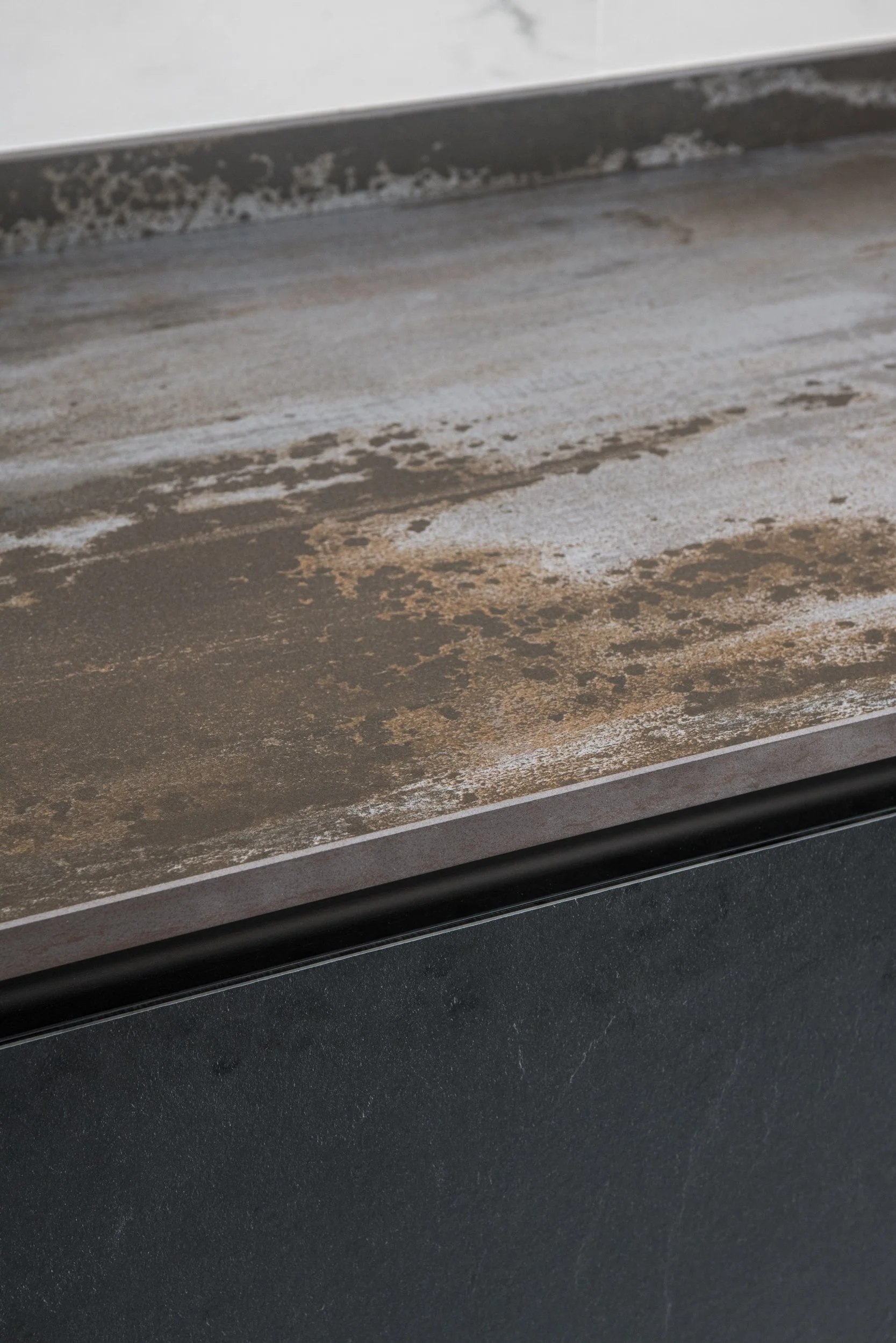 Dettaglio di cucina Stosa moderna con isola, piano di lavoro effetto pietra e rivestimento in gres effetto marmo in appartamento ristrutturato a Palermo.