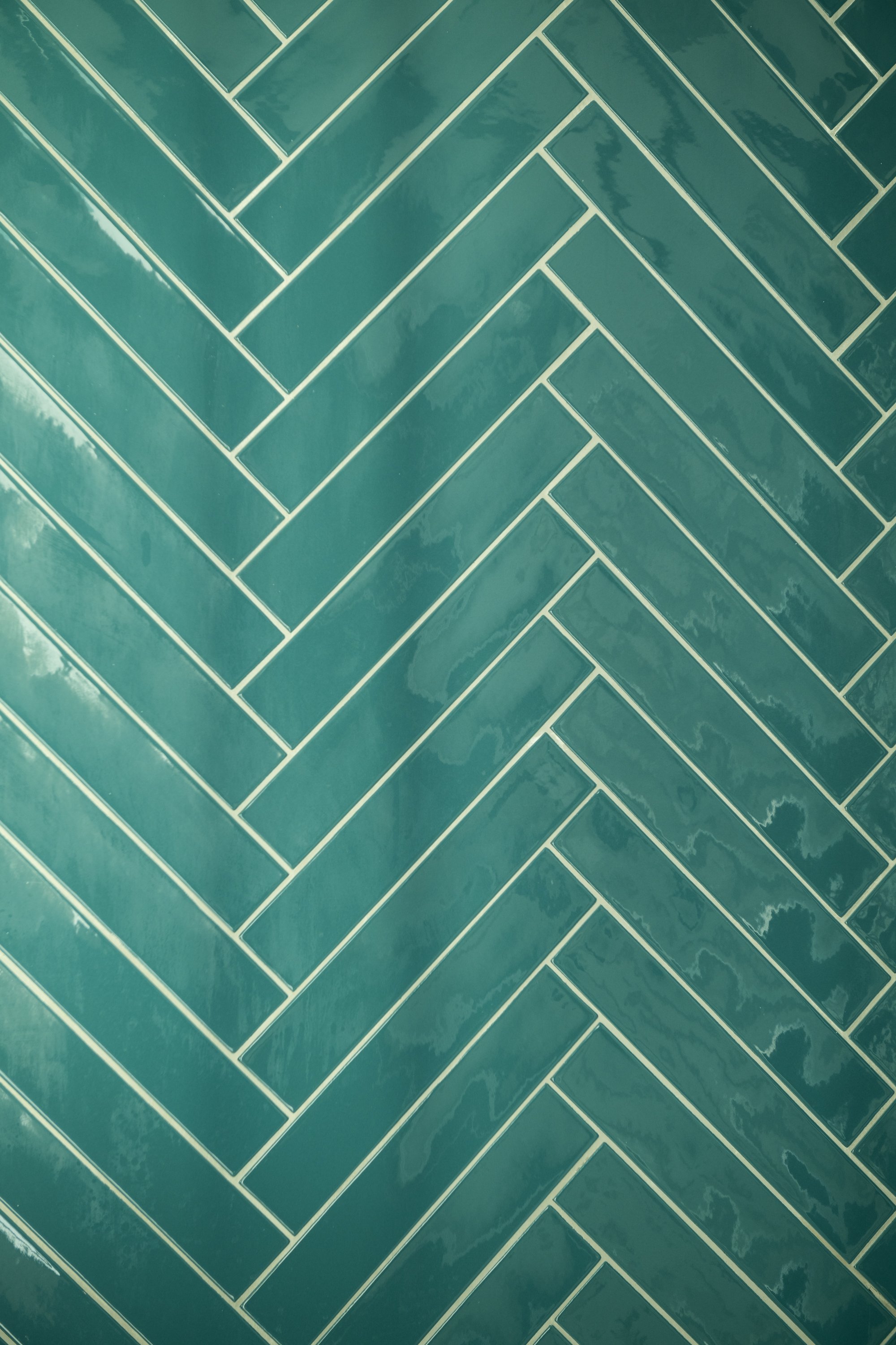 Dettaglio del rivestimento della doccia del bagno padronale in piastrelle ceramiche verde petrolio disposte a spina di pesce a Mondello. La superficie lucida e le variazioni cromatiche delle piastrelle valorizzano il disegno geometrico, creando una t