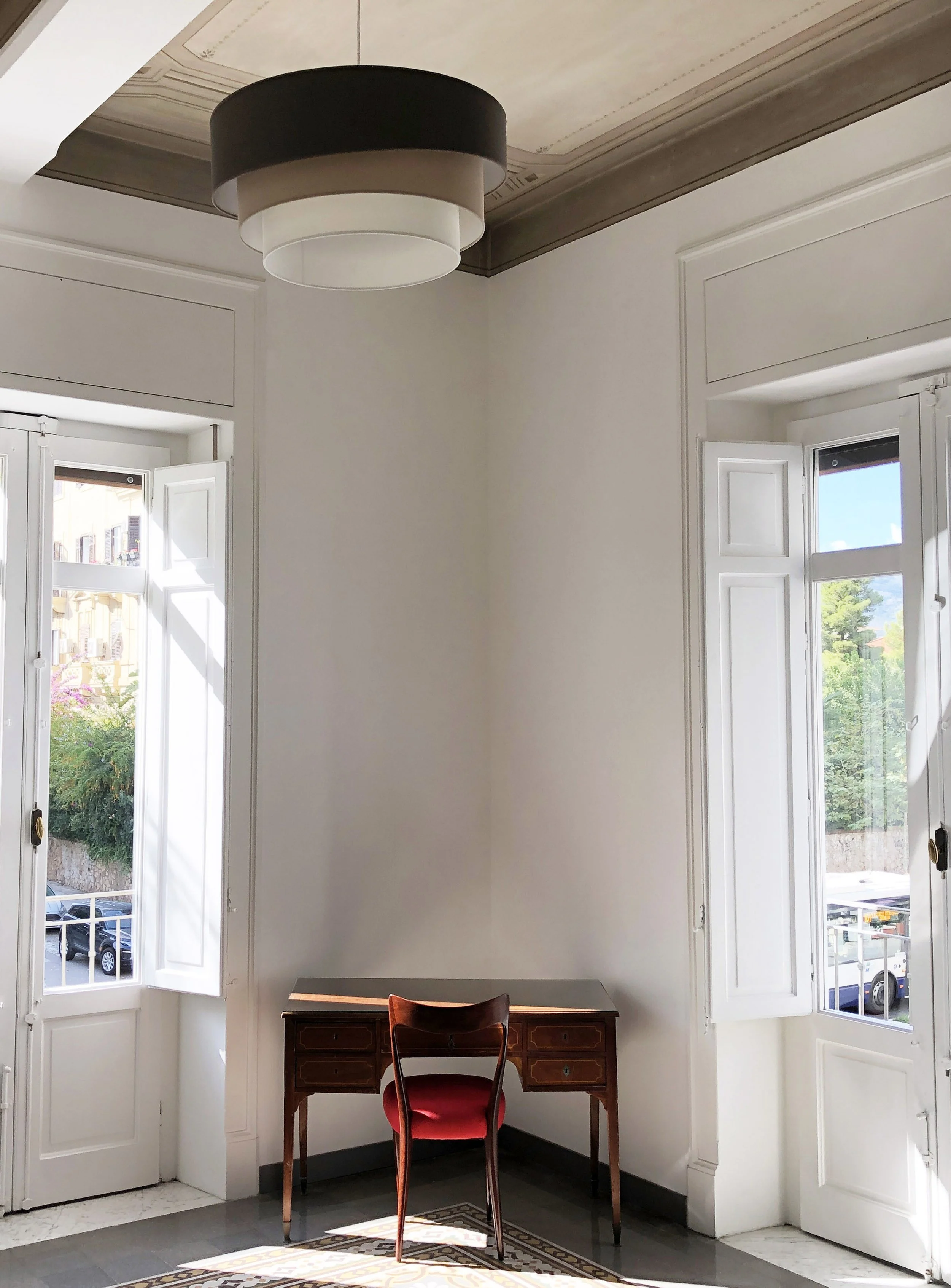Interno di appartamento storico restaurato a Palermo con soffitti decorati recuperati, infissi originali restaurati e pavimento in cementine. La luce naturale proveniente dalle aperture sul prospetto principale valorizza l'altezza degli ambienti e il