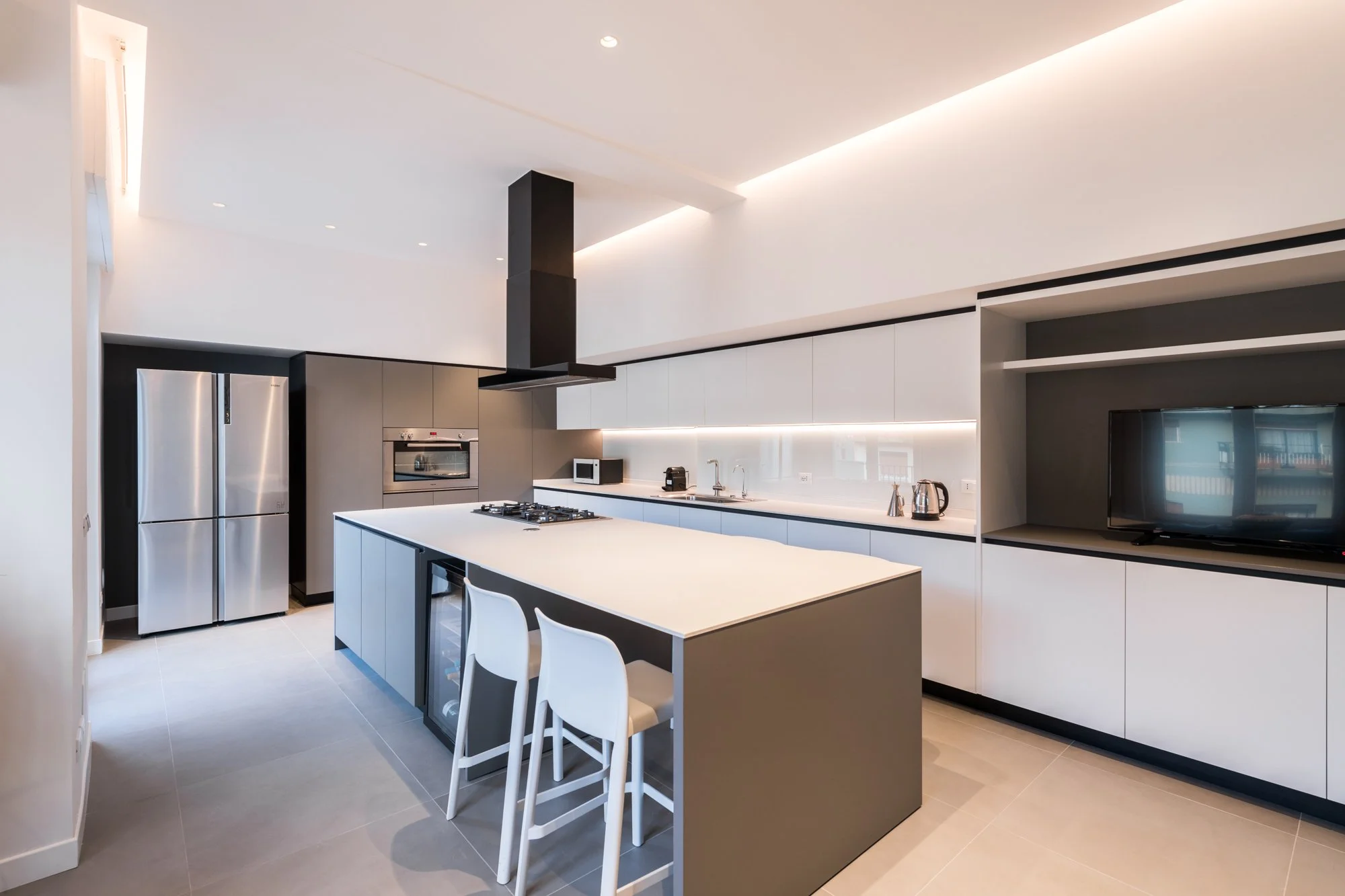 La cucina con isola dell'appartamento a Palermo combina funzionalità e continuità visiva, integrandosi nel sistema di prospettive che mette in relazione gli ambienti della casa.