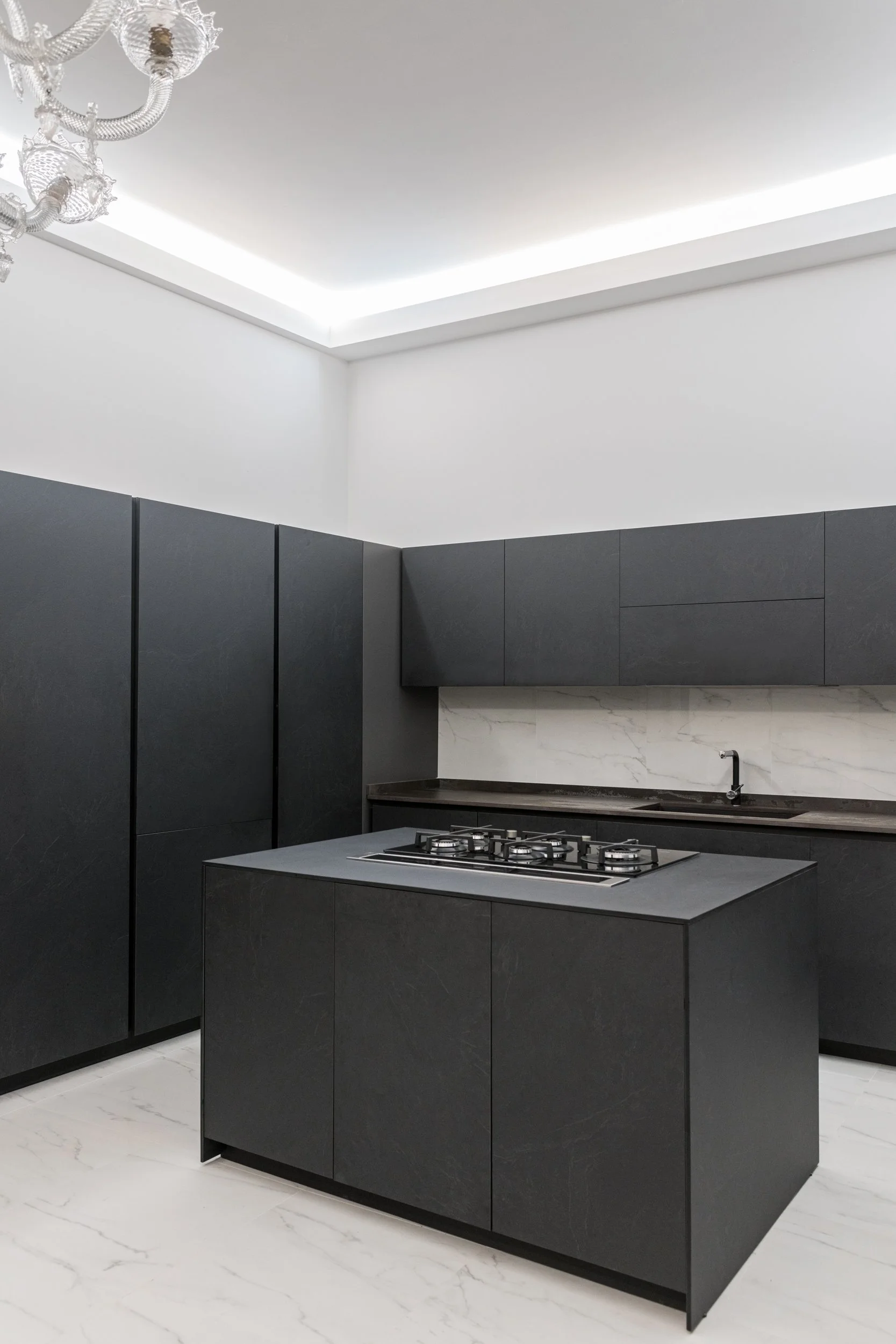 Cucina moderna Stosa con isola centrale, mobili effetto pietra e pavimento in gres effetto marmo in appartamento ristrutturato a Palermo.