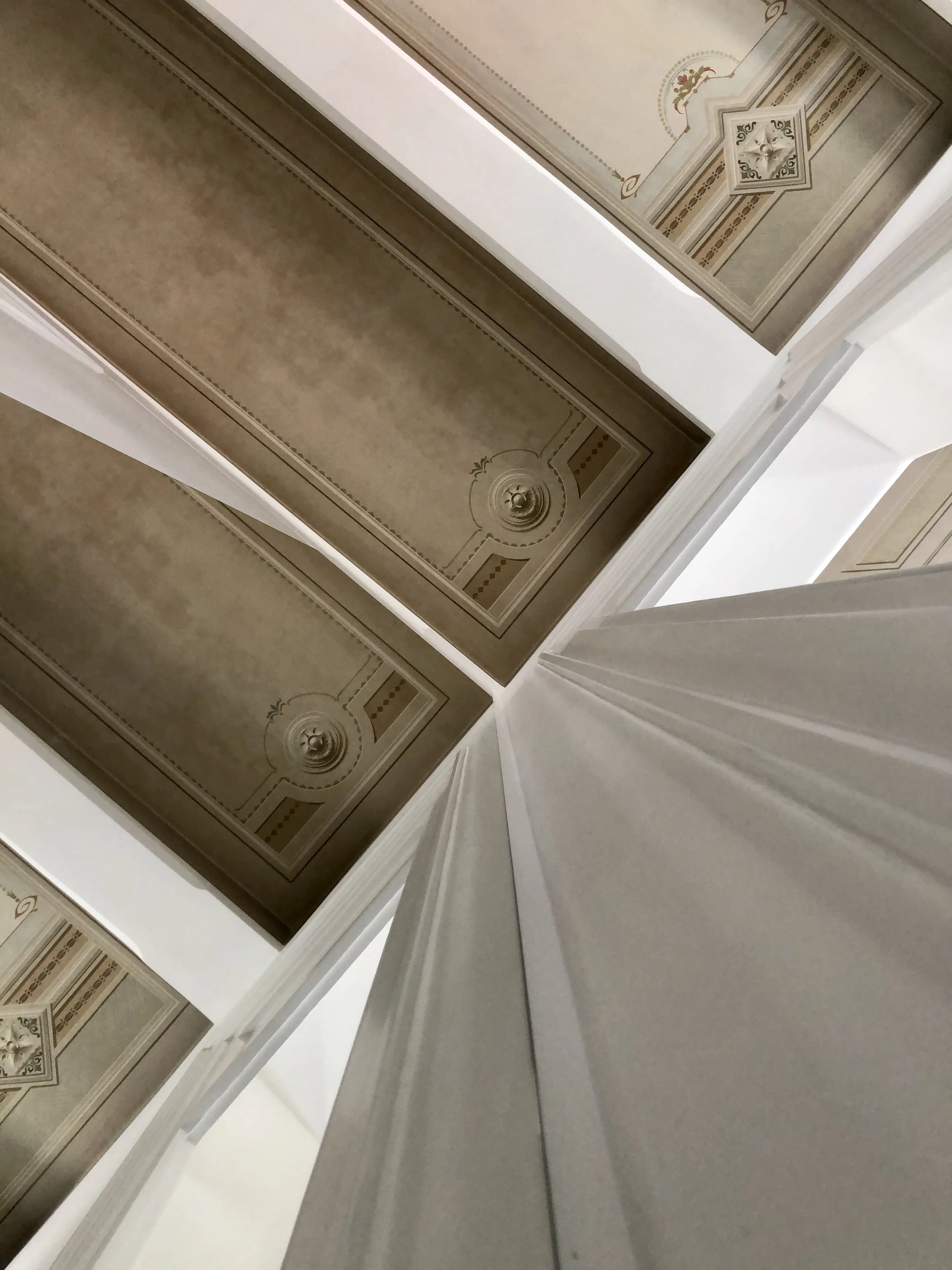 La porta a specchio inserita nel nuovo volume dei servizi diventa un dispositivo spaziale capace di amplificare la luce e riflettere i soffitti dipinti restaurati. Il progetto di restauro dell’appartamento storico a Palermo mette in relazione materia