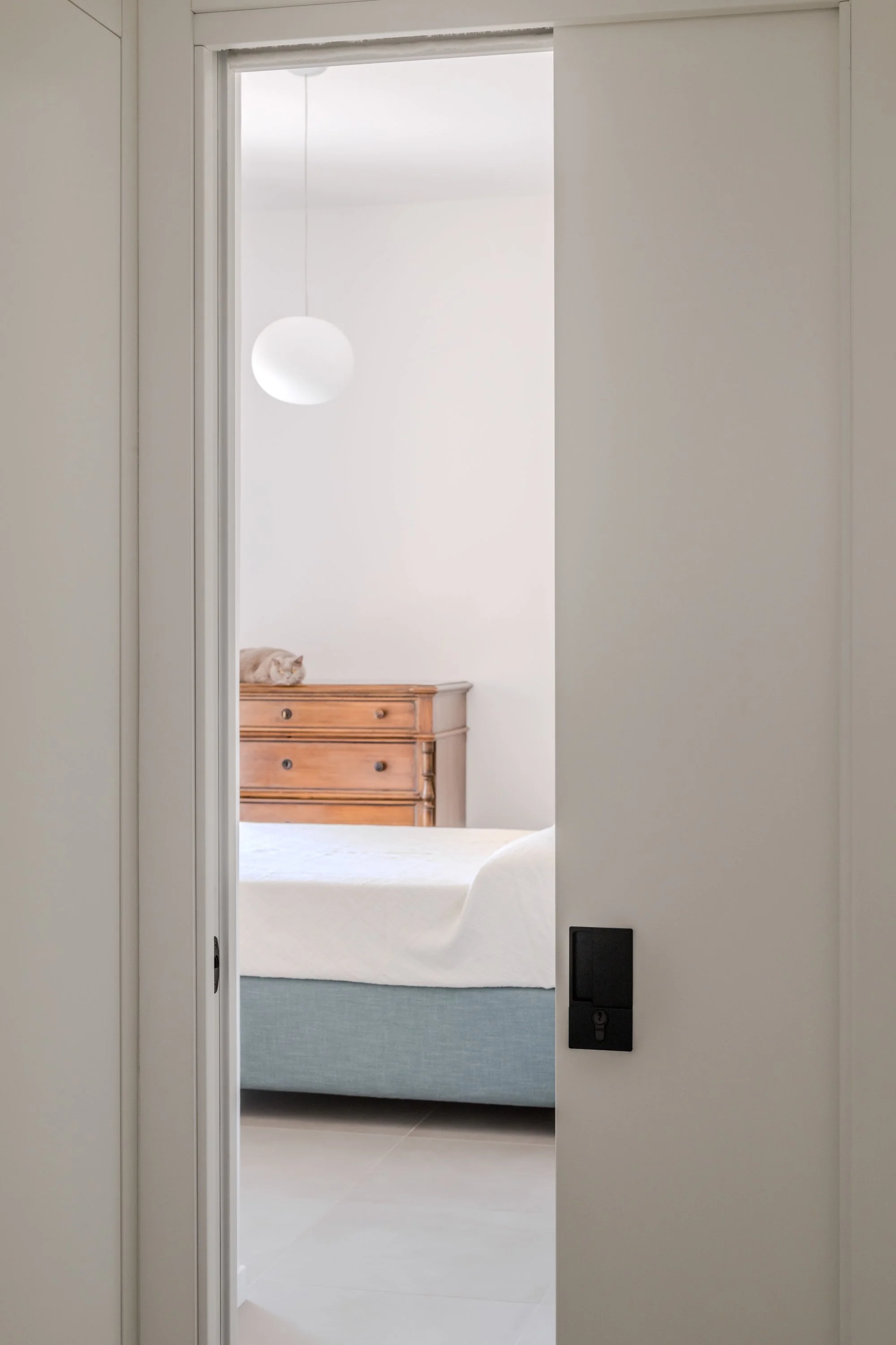 Porta scorrevole integrata che collega il corridoio alla zona notte nel progetto Slide a Palermo di FDR architetto. Il pannello a scomparsa consente di modulare privacy e continuità spaziale, mantenendo il linguaggio essenziale e unitario dell'interv