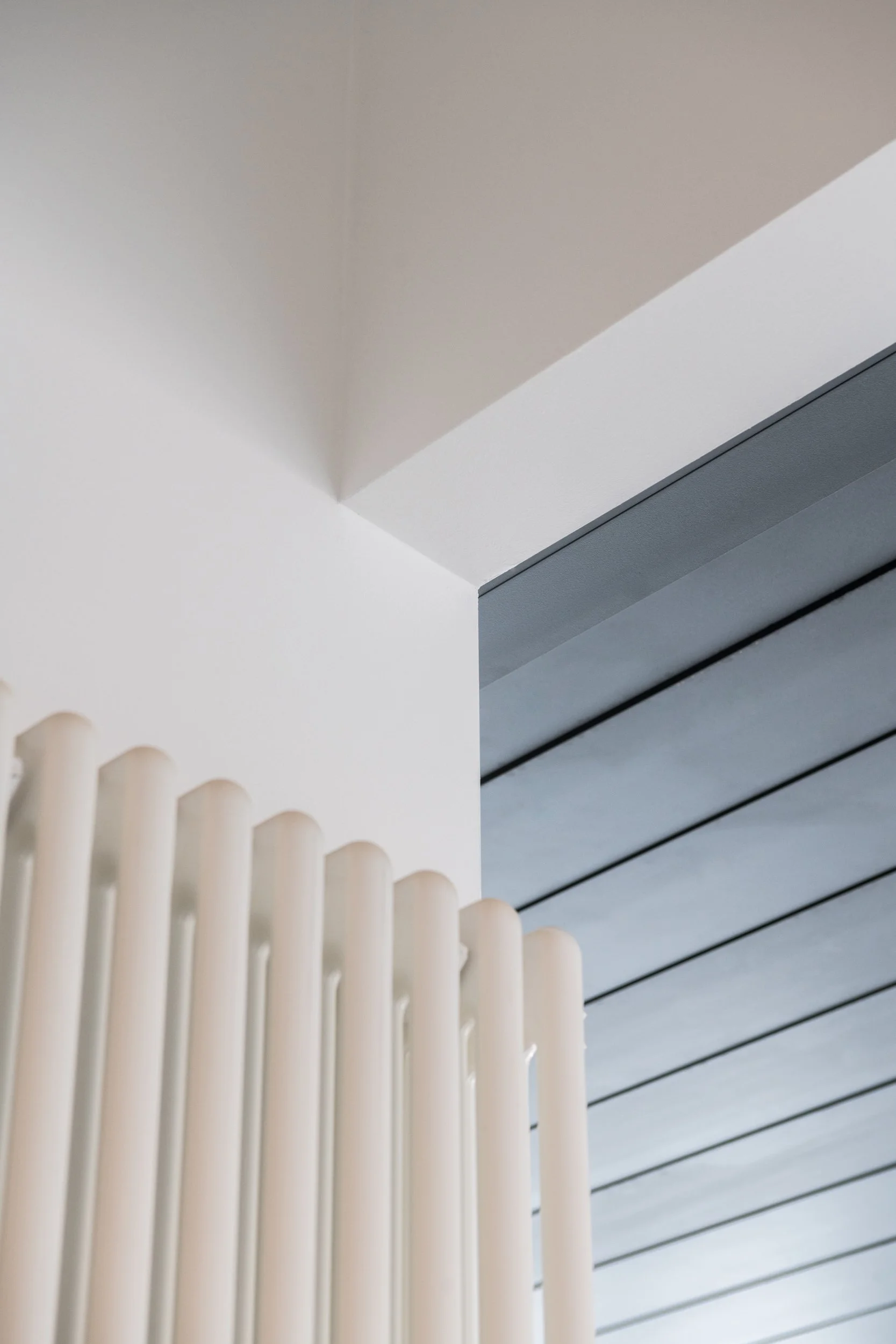 Dettaglio architettonico del progetto Dinamo, intervento di ristrutturazione e risanamento di un appartamento a Palermo. Il radiatore verticale di design dialoga con il controsoffitto dotato di illuminazione indiretta integrata, evidenziando la cura 