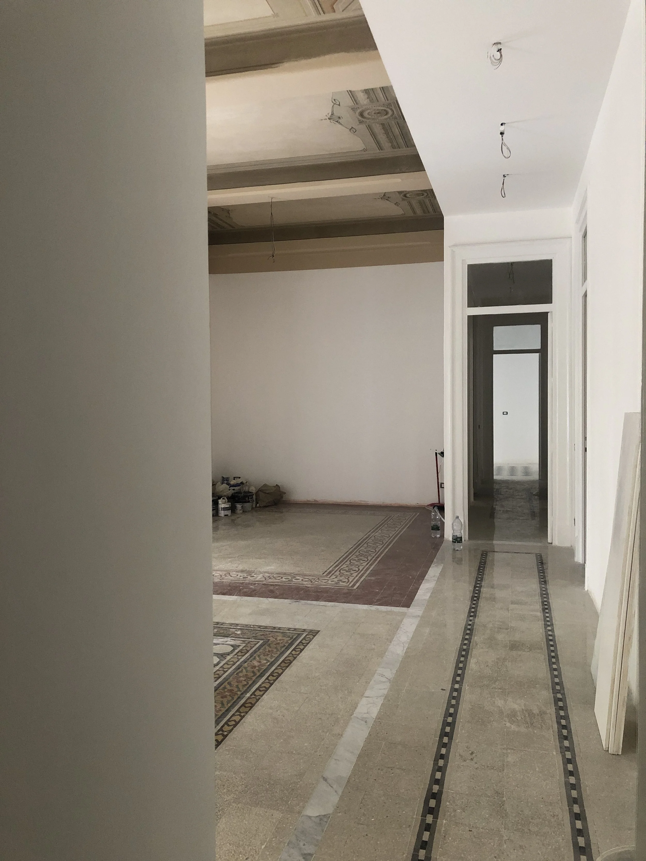 Restauro e riqualificazione di un appartamento storico a Palermo. L'immagine documenta la nuova continuità spaziale ottenuta attraverso il recupero dei pavimenti originali, la ricomposizione dei tappeti decorativi in cementine e la ridefinizione dell