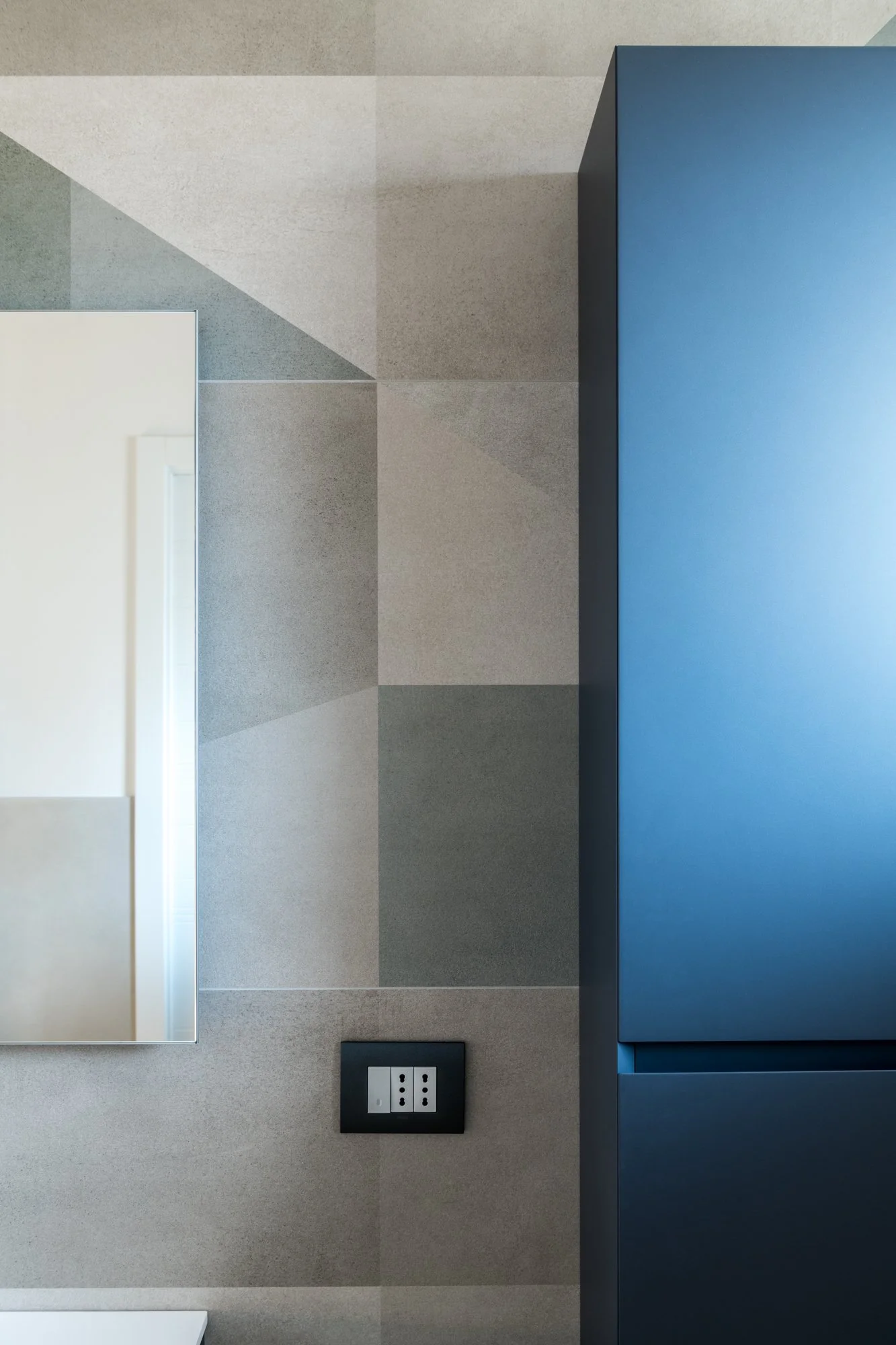 Il rivestimento geometrico in gres dialoga con il mobile sospeso creando un equilibrio tra superfici, volumi e materia. Un dettaglio del bagno padronale del progetto Mikado a Palermo.
