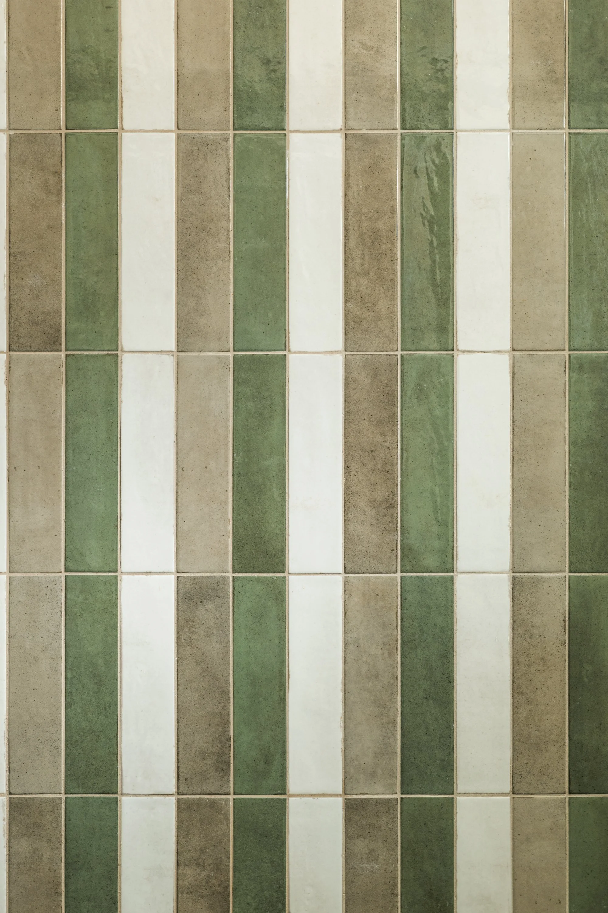 Dettaglio delle piastrelle del bagno di un progetto di interior design a Mondello dello studio FDR Architetto di Francesco Di Raimondo in Sicilia. Il rivestimento alterna piastrelle rettangolari nei toni del verde, beige e bianco, disposte verticalme