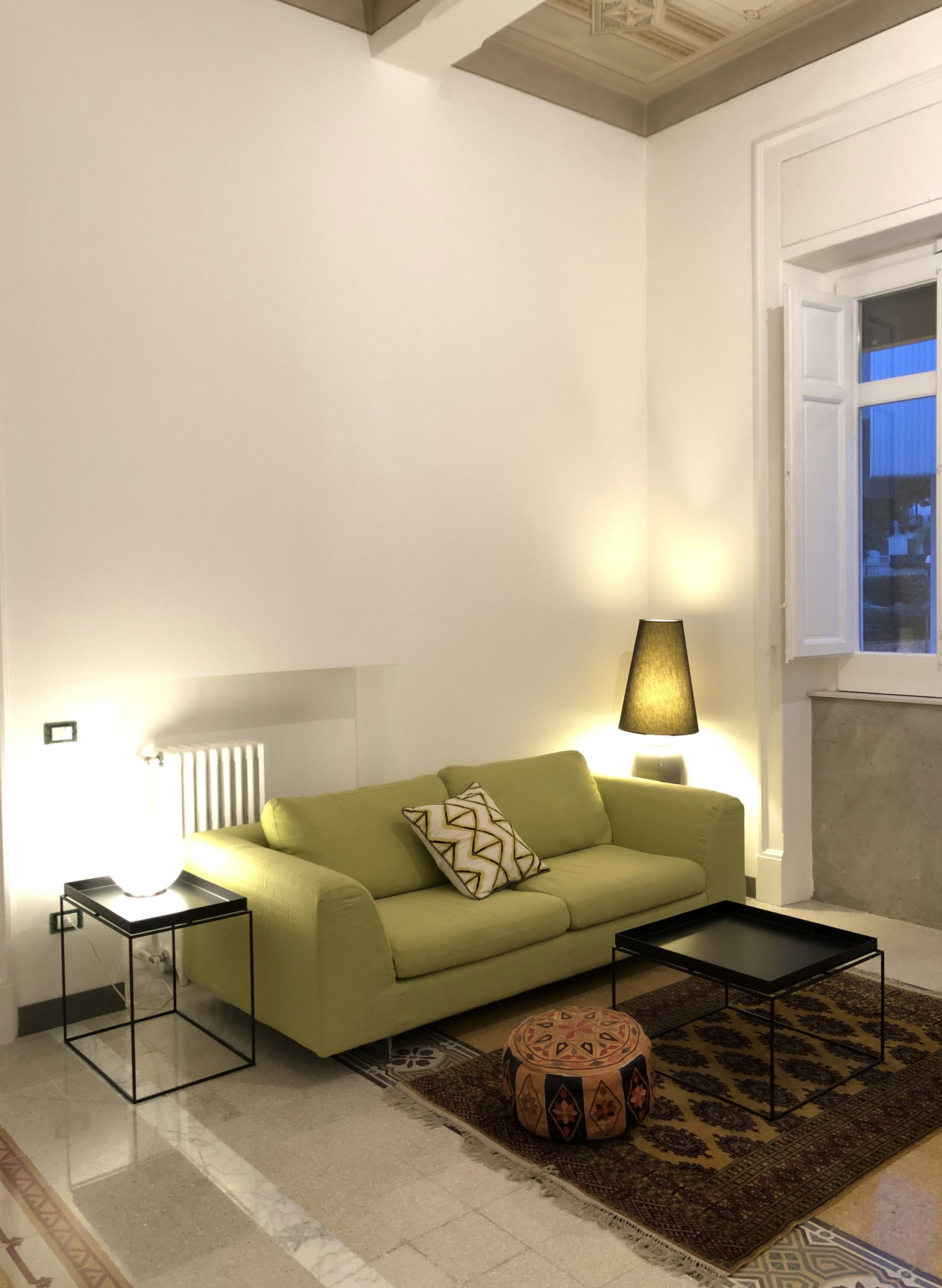 Salotto contemporaneo realizzato all'interno di un appartamento storico restaurato a Palermo. I soffitti decorati originali, le pavimentazioni storiche recuperate e le ampie aperture definiscono uno spazio luminoso nel quale architettura storica e in