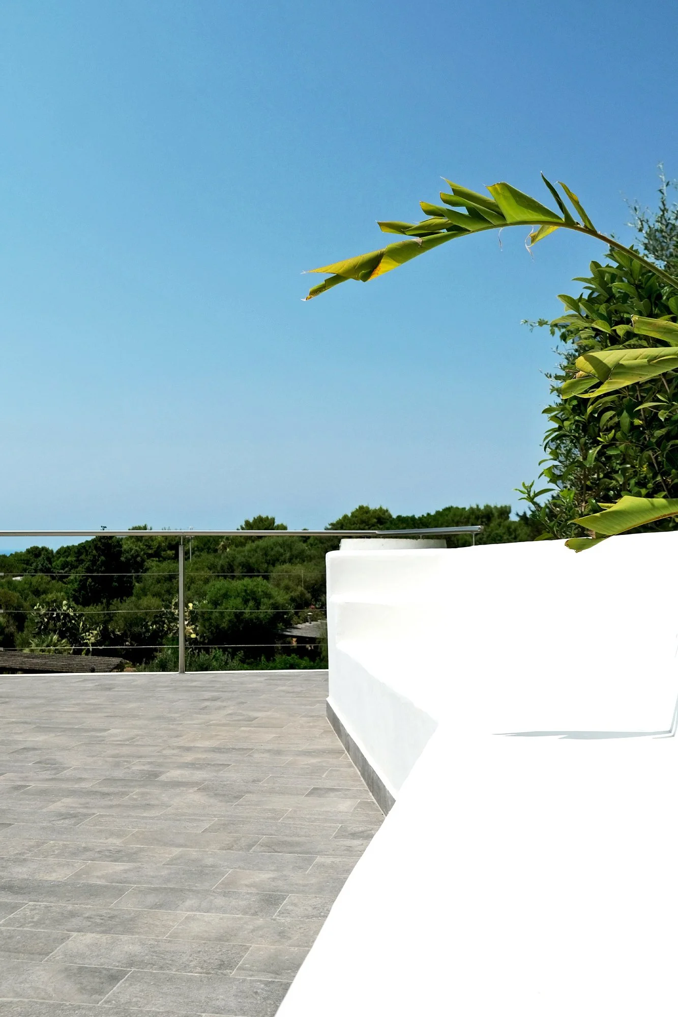 Riqualificazione degli spazi esterni di una villa a Ustica con terrazza panoramica vista mare. Materiali effetto pietra, superfici bianche e dettagli in acciaio inox dialogano con la luce mediterranea e il paesaggio costiero, valorizzando il rapporto