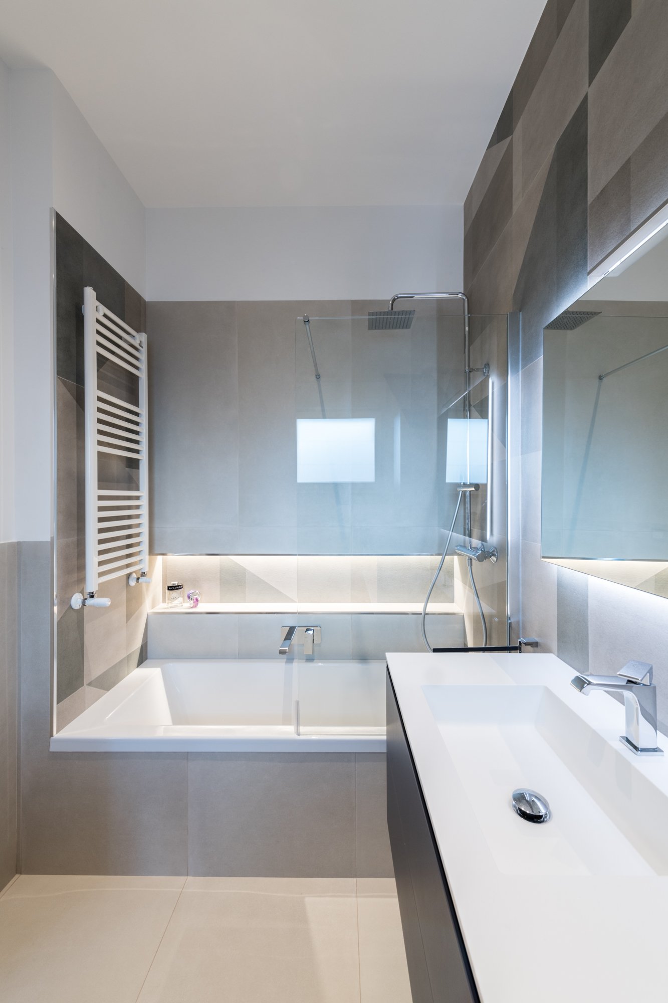 Il bagno padronale del progetto Mikado a Palermo combina superfici neutre e rivestimenti geometrici in gres per costruire uno spazio equilibrato tra luce, materia e percezione. Vasca, illuminazione integrata e dettagli sospesi definiscono un ambiente