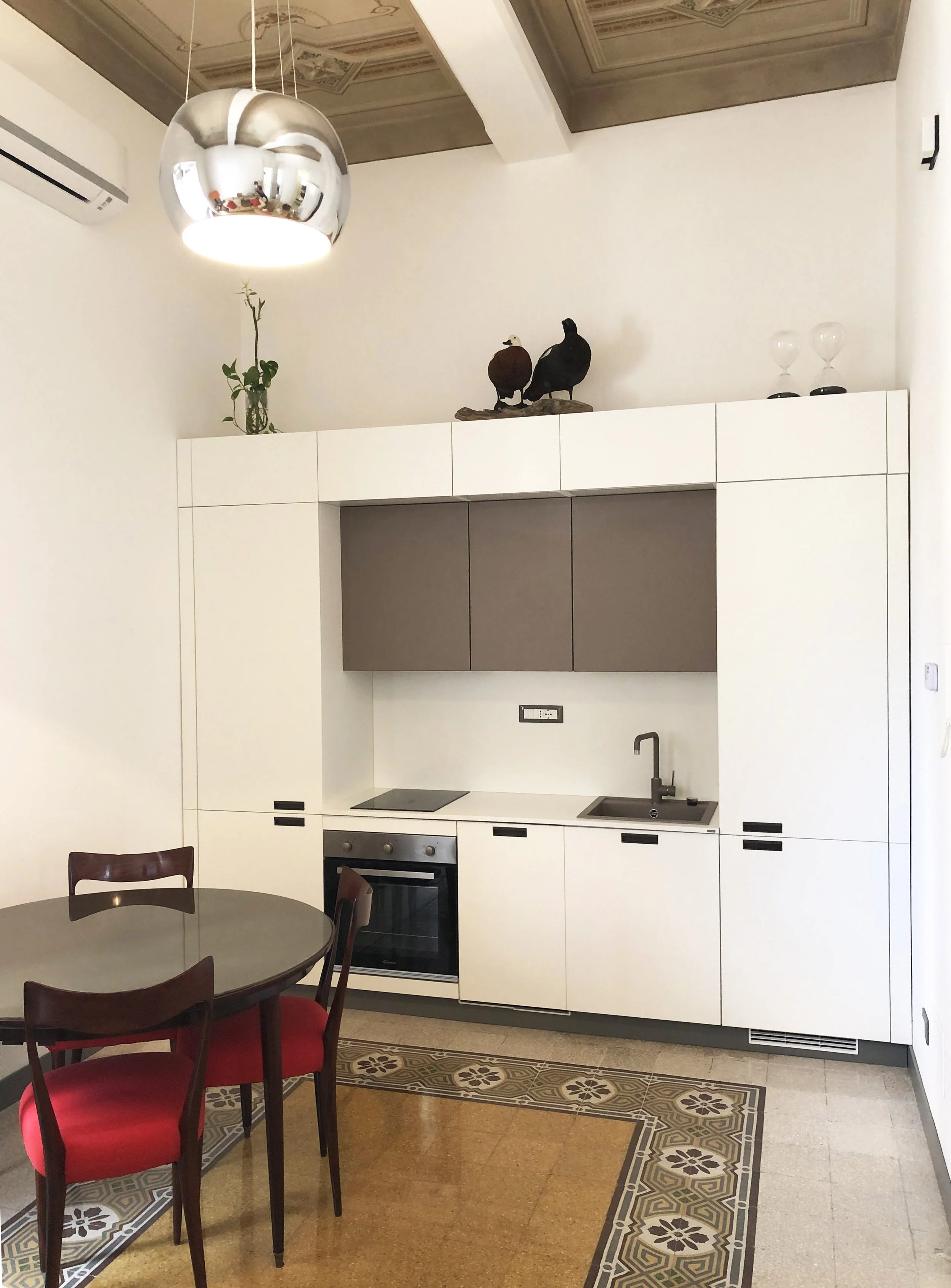 Cucina su misura realizzata nel restauro di un appartamento storico a Palermo. L'intervento integra arredi contemporanei, pavimenti in cementine originali restaurati e soffitti decorati ottocenteschi recuperati, trasformando la memoria dell'abitazion