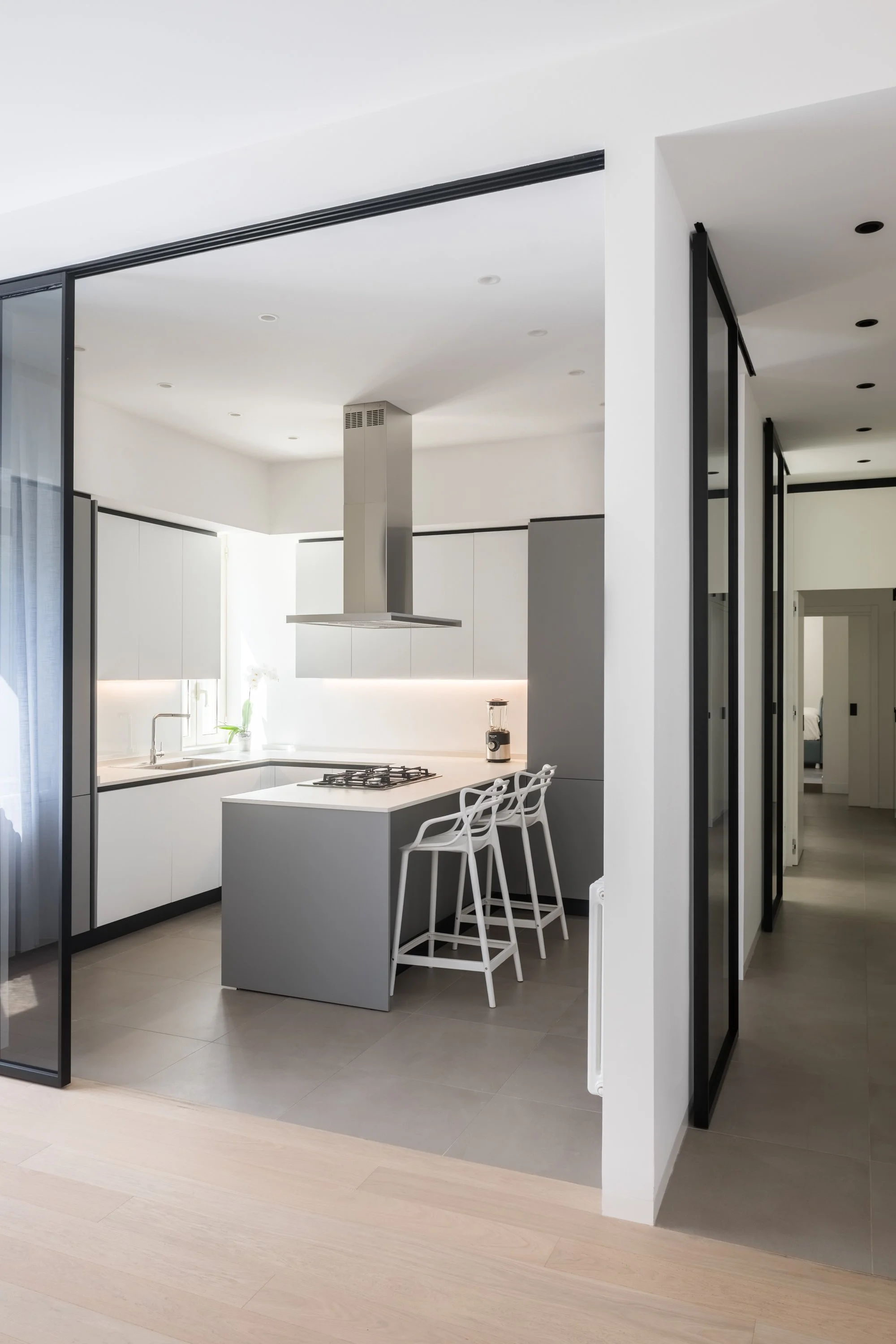 Cucina Stosa in un appartamento ristrutturato a Palermo, definita da porte vetrate scorrevoli che regolano il rapporto con gli ambienti circostanti. Le superfici trasparenti permettono di modulare apertura e privacy mantenendo continuità visiva e per