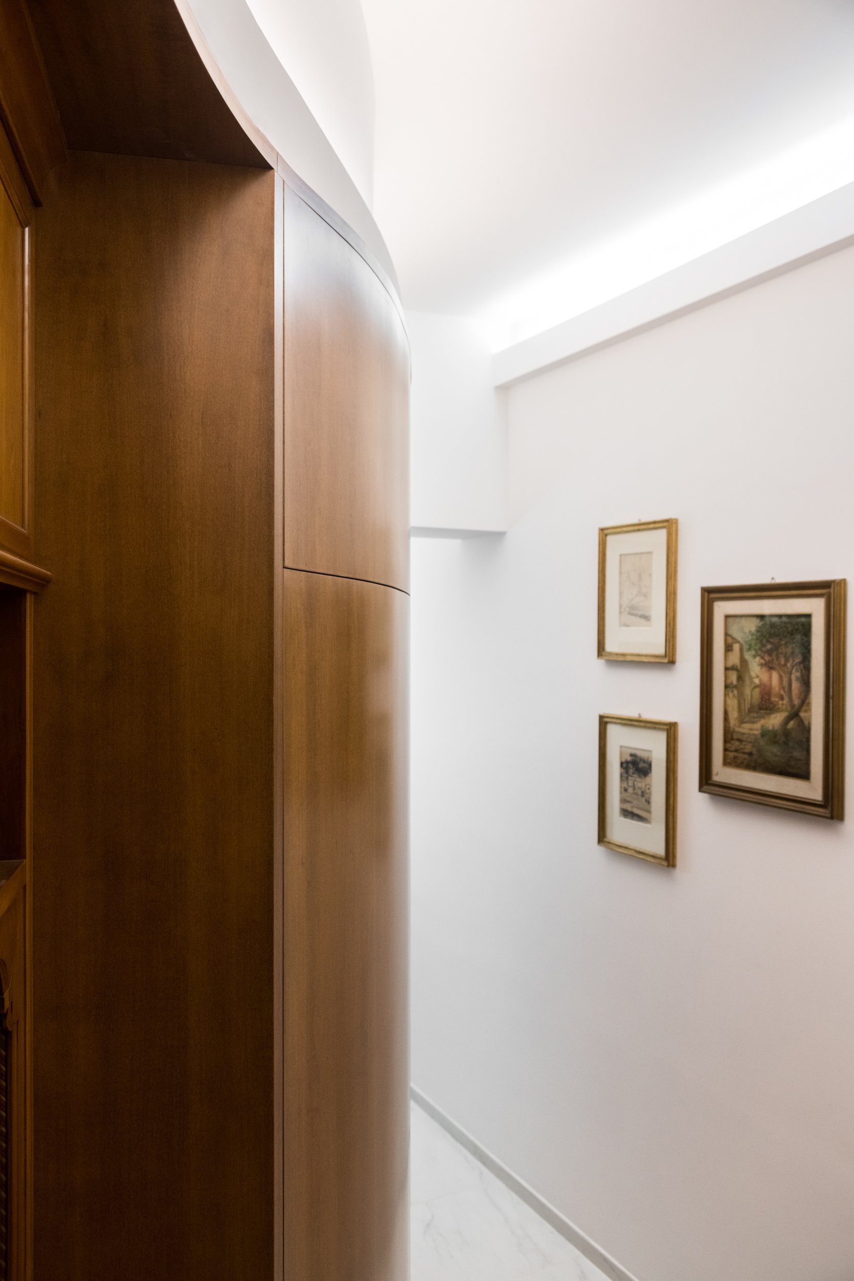 Corridoio con libreria curva su misura e falegnameria integrata nel progetto Dinamo, ristrutturazione e risanamento di appartamento nel centro storico di Palermo.