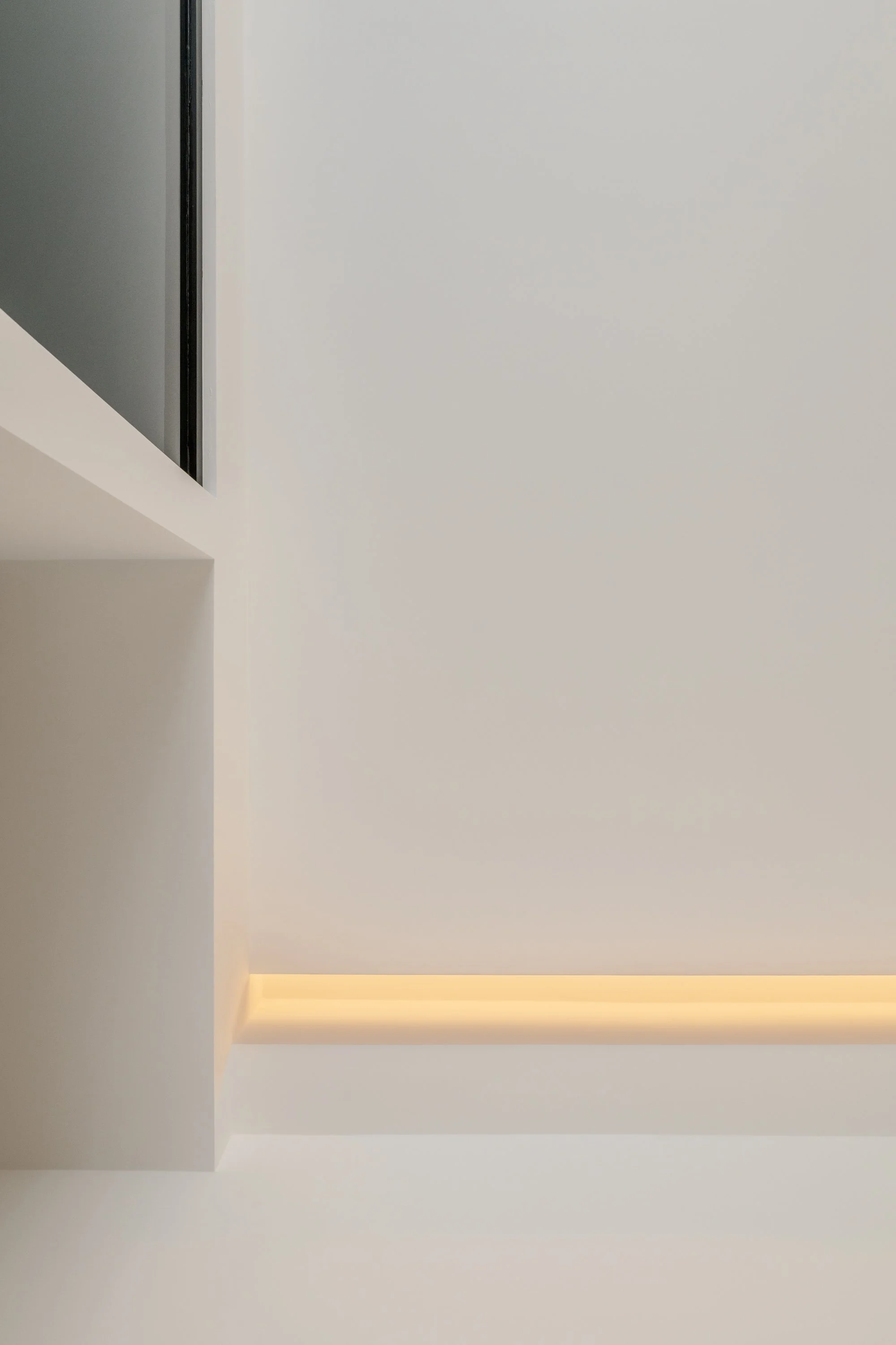 I tagli di luce integrati nel soffitto trasformano l’illuminazione in un elemento architettonico che accompagna la geometria e la percezione dello spazio.