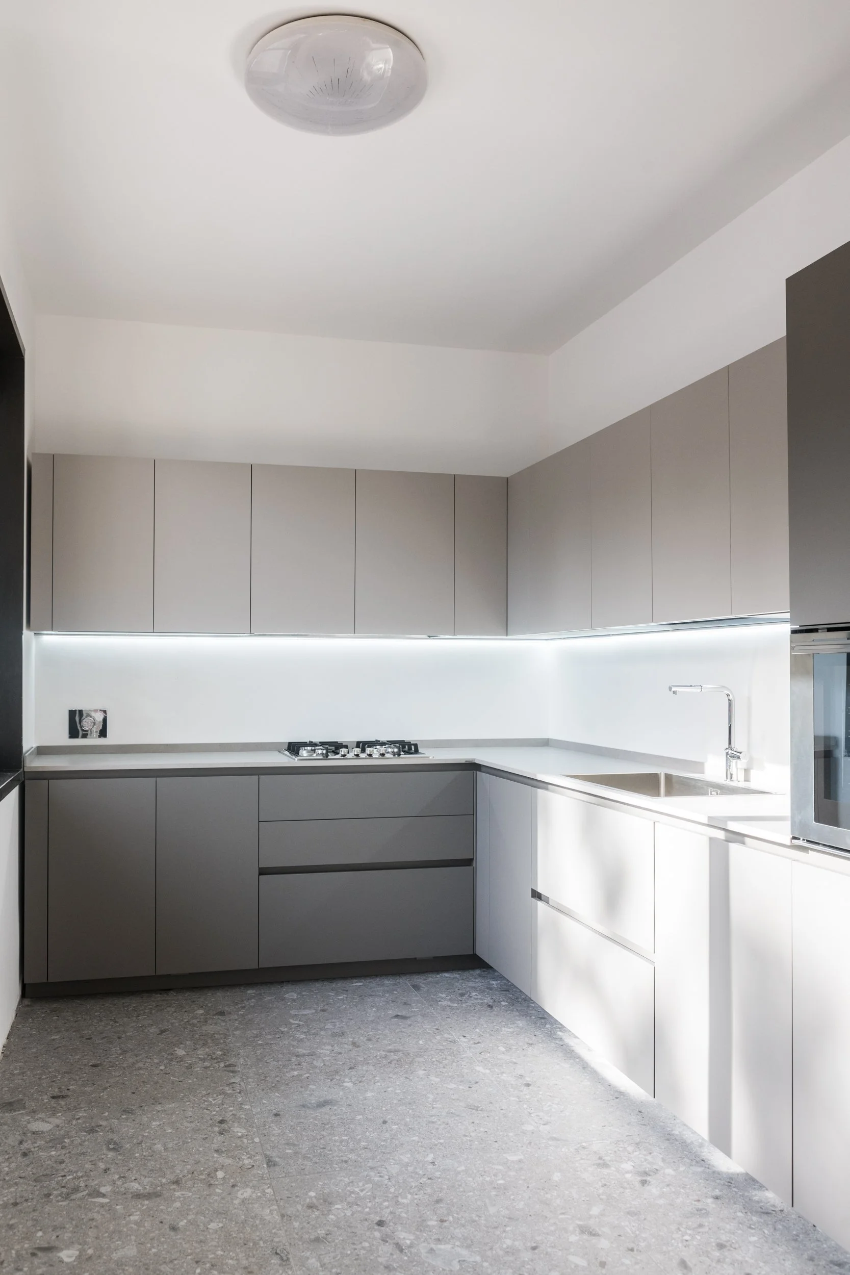 La cucina è uno degli ambienti integralmente riprogettati da Francesco Di Raimondo Architetto all'interno della villa ristrutturata a Palermo. Volumi essenziali, materiali neutri e illuminazione integrata definiscono uno spazio contemporaneo in conti
