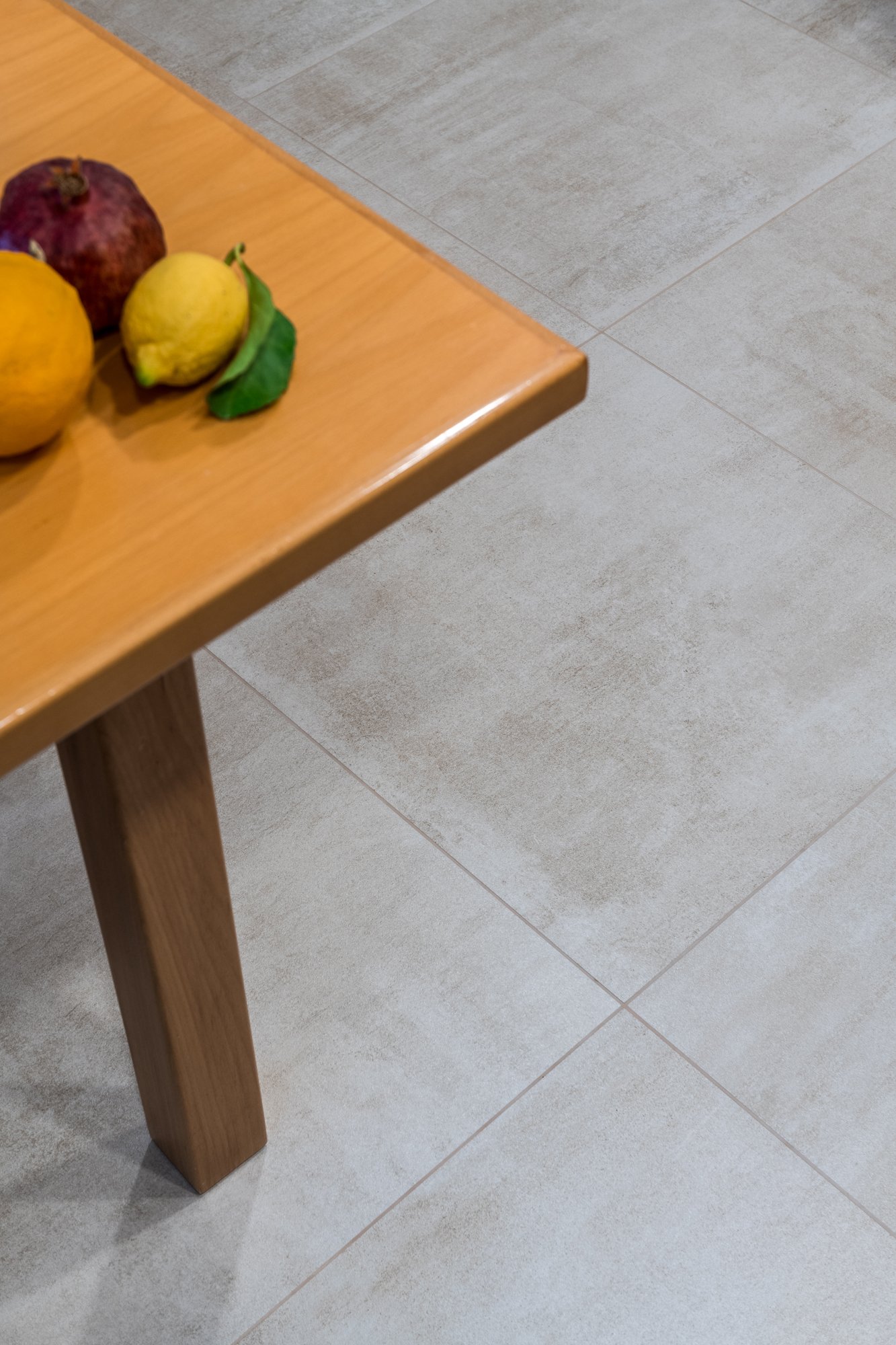 Il gres porcellanato dialoga con gli arredi in legno naturale definendo continuità materica e comfort abitativo. Un dettaglio del progetto Mikado a Palermo dove superfici, luce e materiali concorrono alla qualità dello spazio interno.