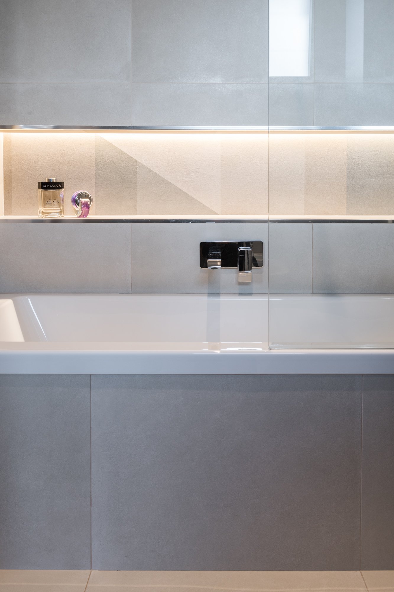 La nicchia retroilluminata valorizza la composizione geometrica del rivestimento in gres e definisce una relazione tra luce e materia. Un dettaglio del bagno padronale del progetto Mikado a Palermo.