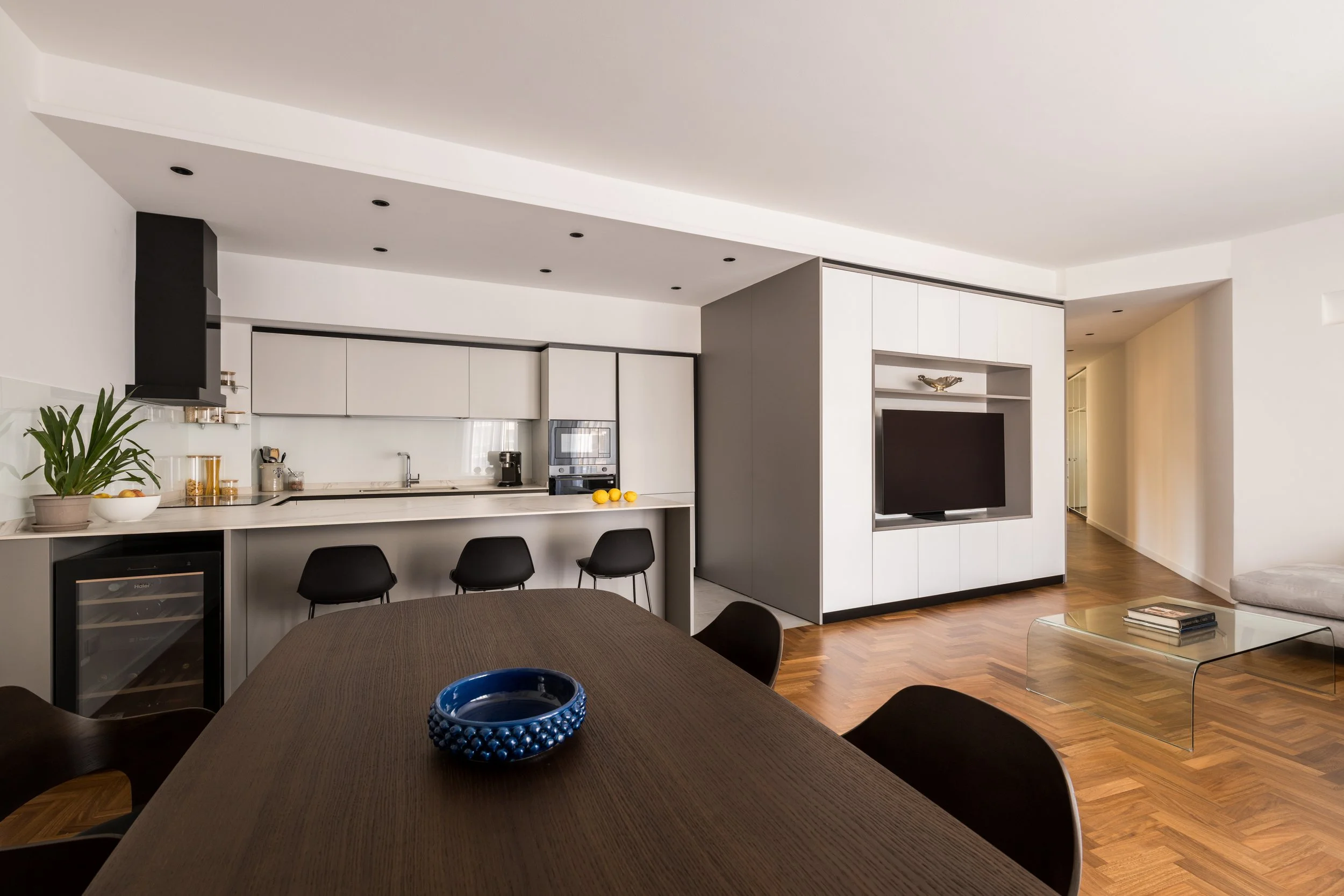 Il volume centrale su misura organizza la distribuzione dell’appartamento a Palermo mettendo in relazione la zona giorno con il corridoio che conduce agli ambienti privati. La cucina con isola, il mobile contenitore integrato e la parete TV definisco