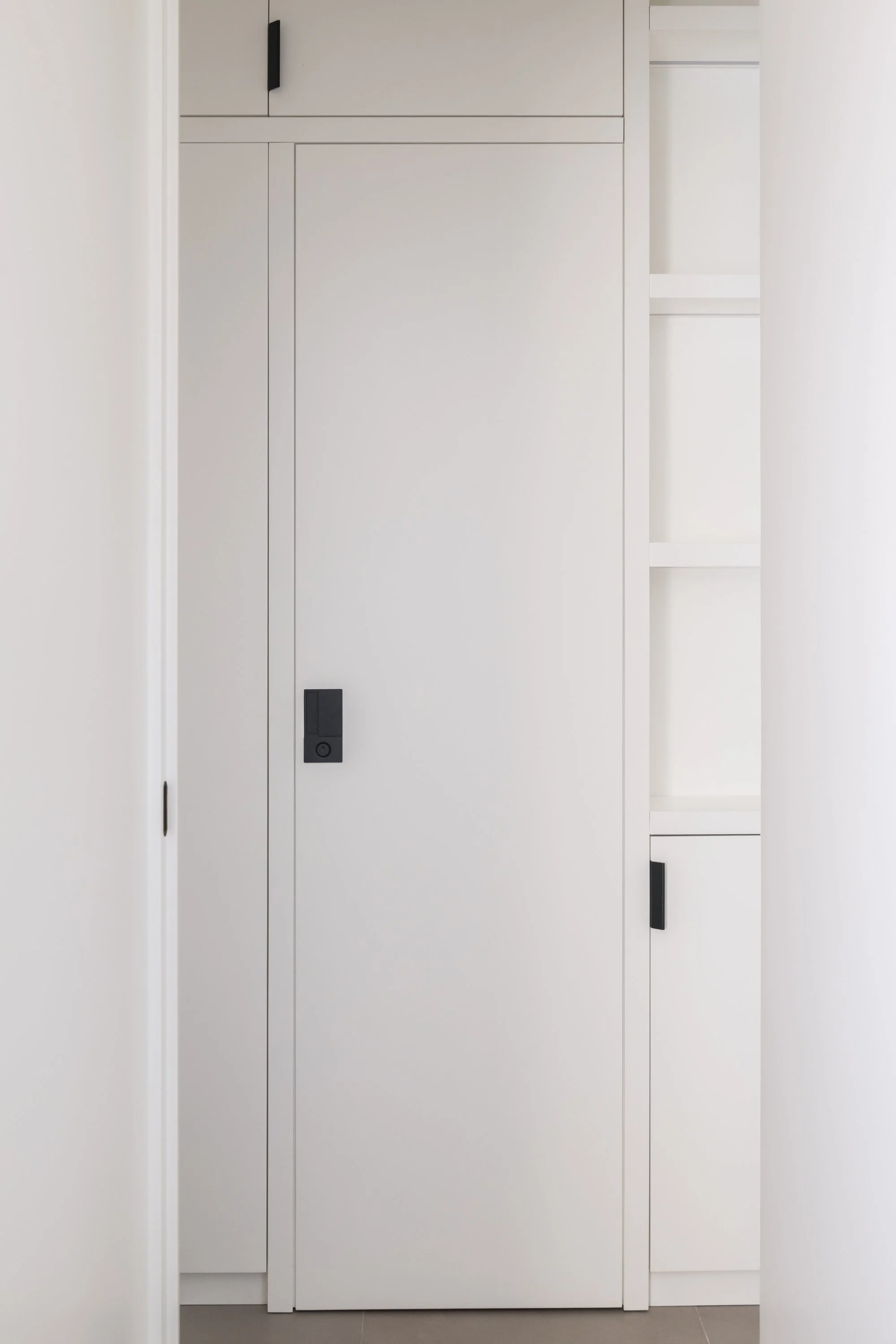 Porta integrata nella falegnameria su misura del progetto Slide a Palermo. La chiusura del bagno è completamente assorbita all'interno del sistema di armadiature, trasformando una funzione tecnica in una superficie continua e ordinata.