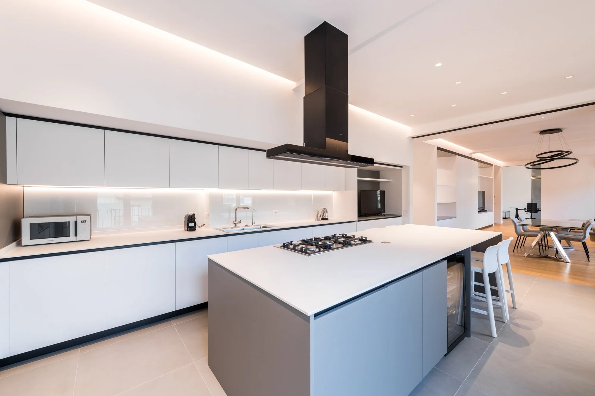 La cucina con isola dell'appartamento a Palermo si integra alla zona giorno attraverso il sistema di porte a vetri scorrevoli, mantenendo continuità visiva e funzionale tra preparazione, convivialità e soggiorno.