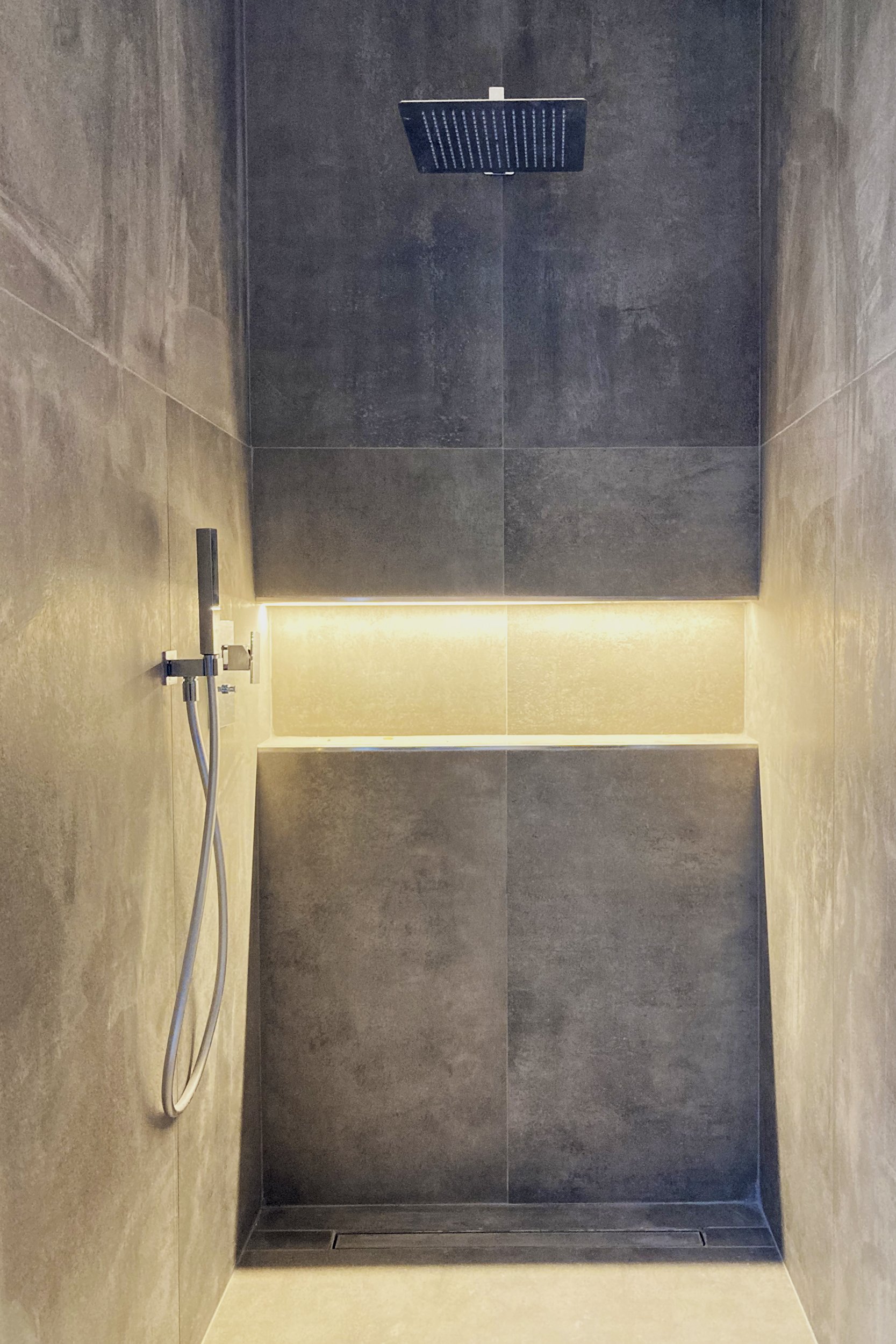 Superfice materica che ricorda il cemento in questa doccia con nicchia e striscia led nel progetto Tornasole a Palermo di FDR archietto.