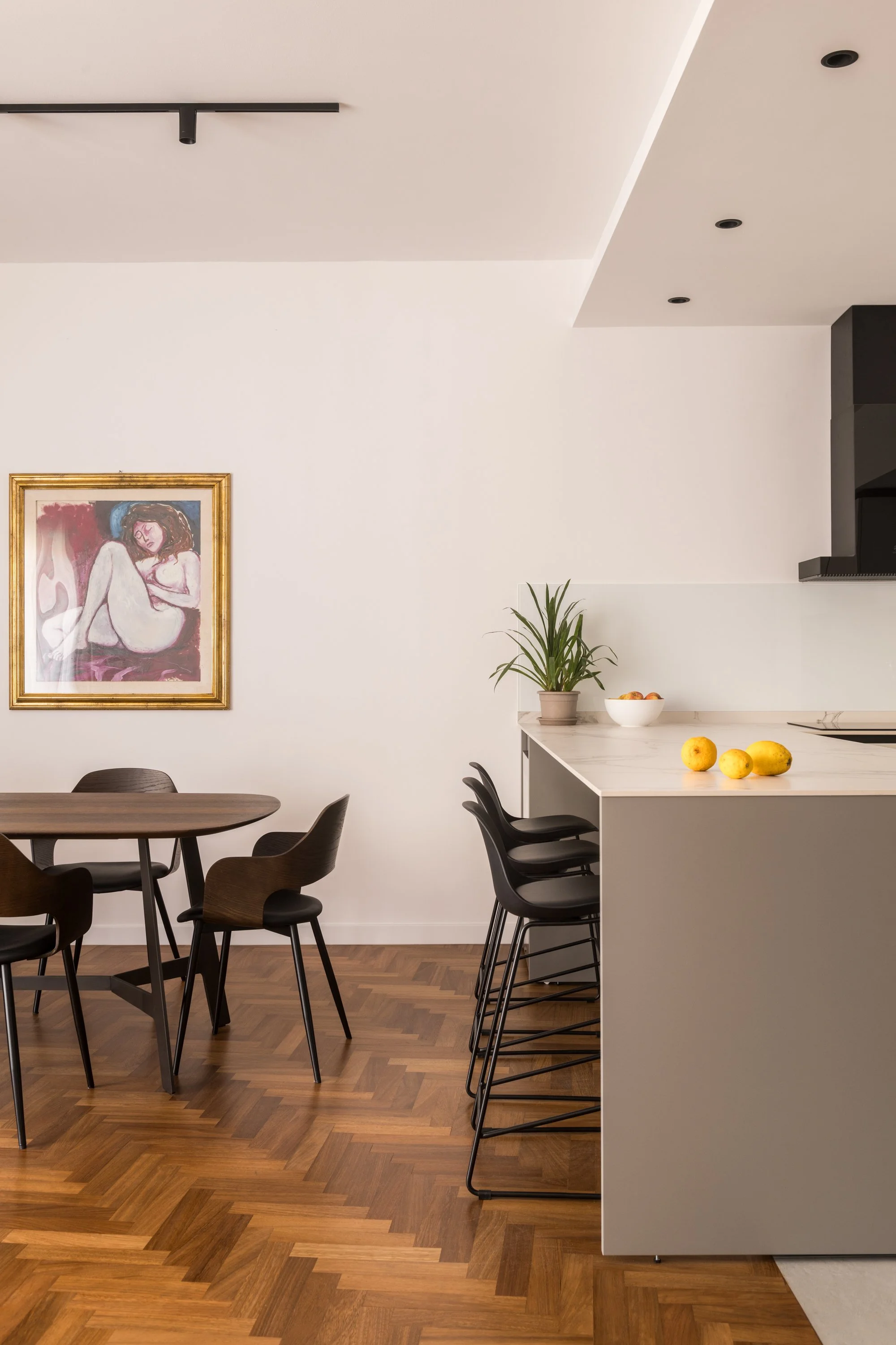 Open space contemporaneo con illuminazione architettonica integrata, volume centrale su misura, cucina con isola e parquet in iroko a spina.