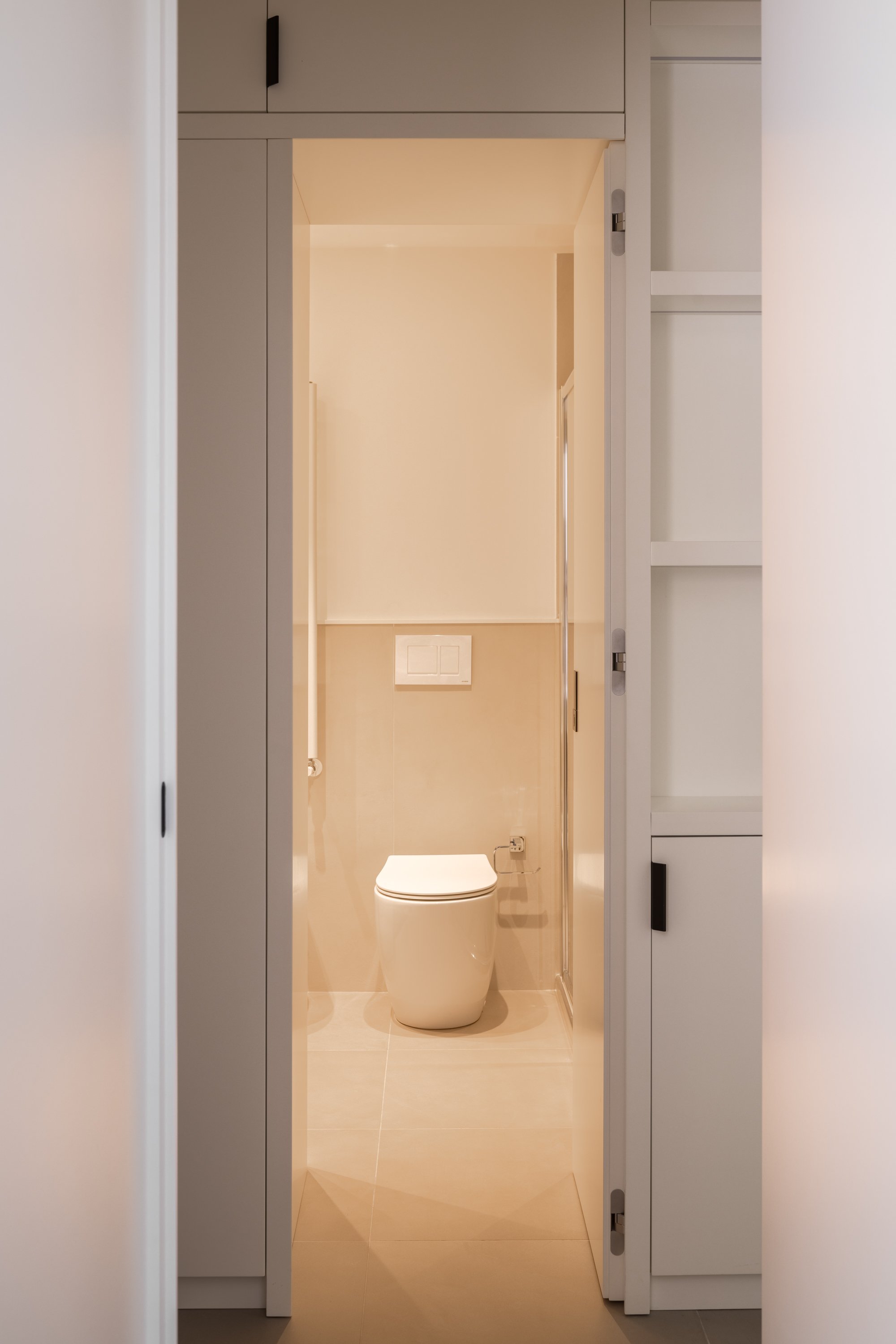 Nel progetto Slide, il bagno si inserisce all'interno del sistema di falegnameria che struttura il corridoio e organizza gli spazi di servizio. L'apertura della porta rivela un ambiente compatto e luminoso, concepito come naturale estensione dell'arc
