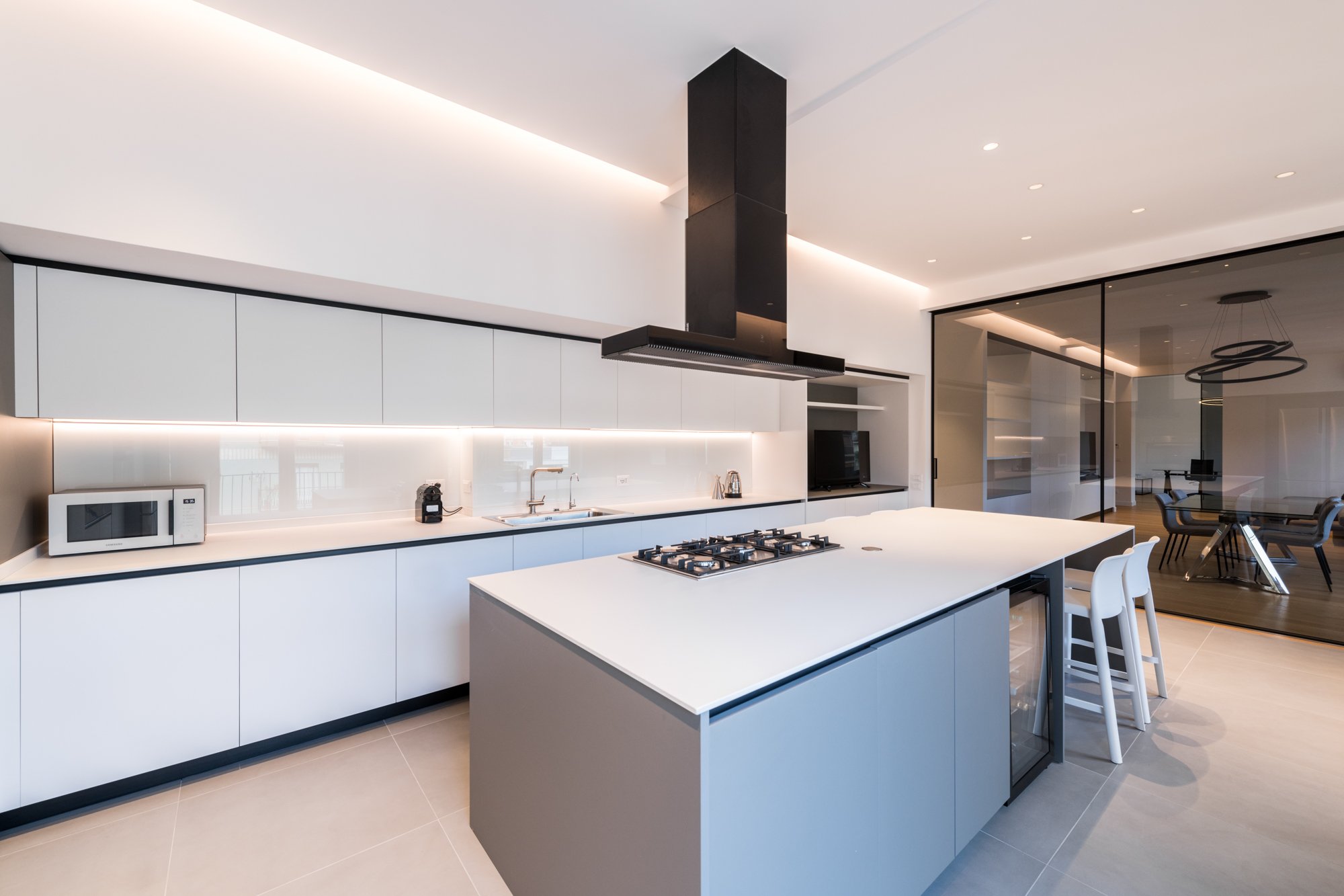 La cucina con isola dell'appartamento a Palermo si chiude dalla zona giorno, con la chiusura della porta a vetri senza però perdere la sequenza di spazi e la continuità degli ambienti.