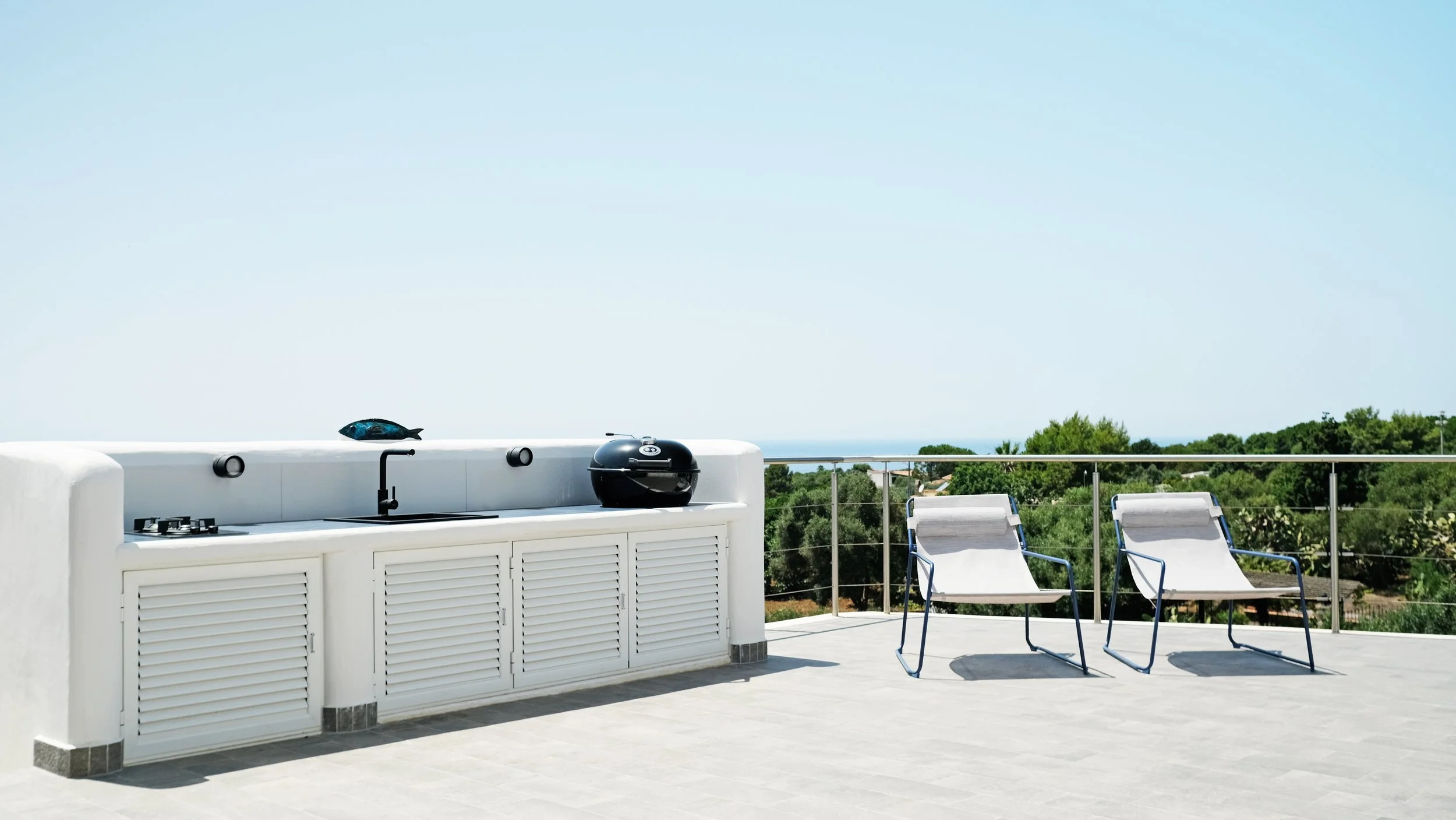La terrazza ad Ustica si configura come un dispositivo di osservazione del paesaggio. Pochi elementi essenziali — pavimentazione, parapetto e arredi — definiscono uno spazio aperto che orienta costantemente lo sguardo verso il mare.