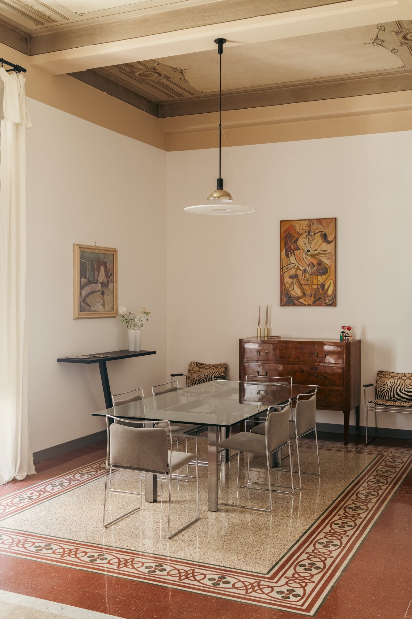 La sala da pranzo dell'appartamento a Palermo combina pavimenti storici e soffitti decorati restaurati con arredi di design e opere d'arte, valorizzando il dialogo tra memoria e contemporaneità. La cura di Francesco Di Raimondo architetto verso l'int