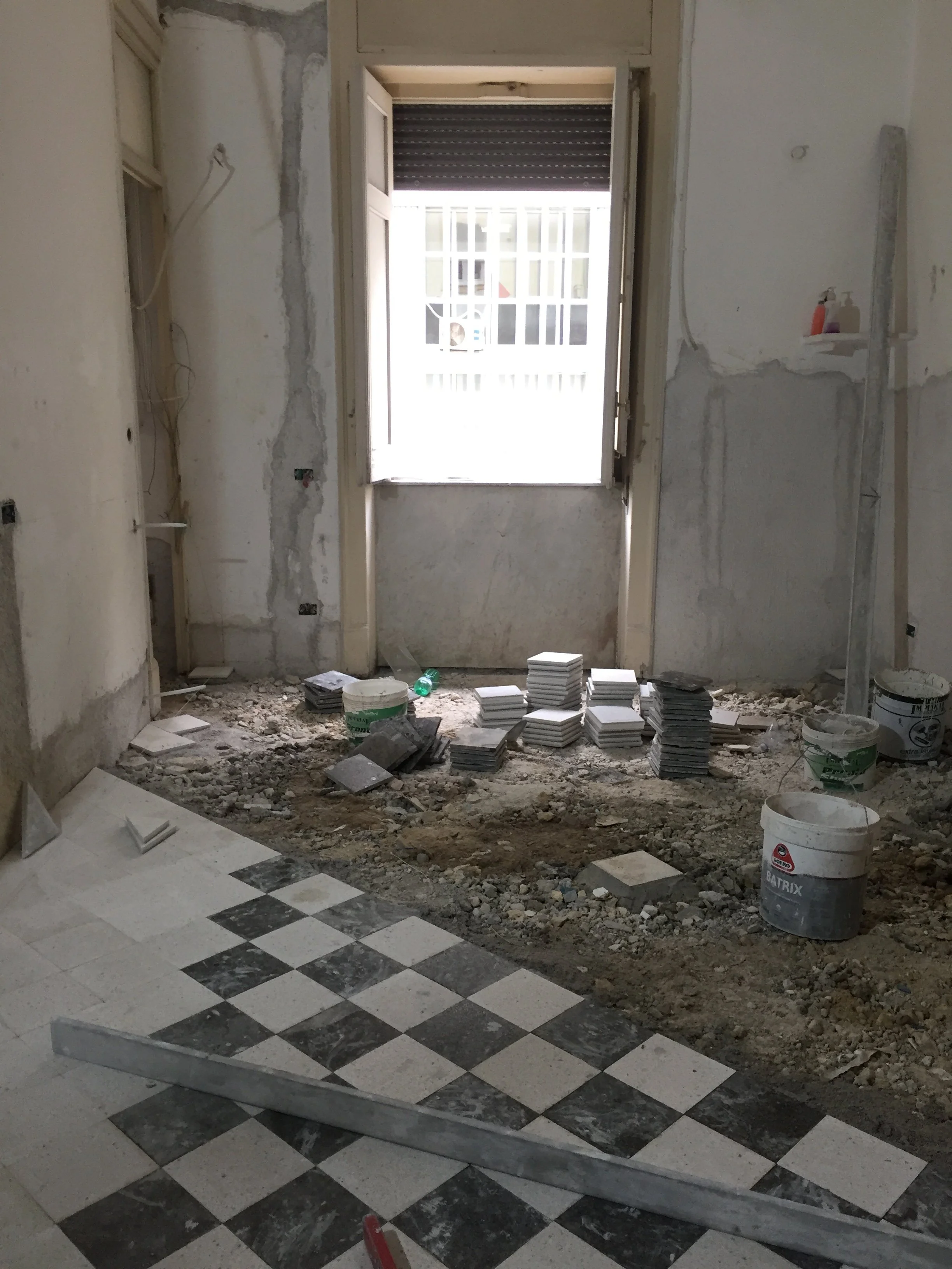 Posa del nuovo pavimento in marmo durante il restauro e la riqualificazione di un appartamento d'epoca a Palermo. Il disegno geometrico a scacchiera accompagna la trasformazione della distribuzione interna e introduce una nuova identità spaziale in d