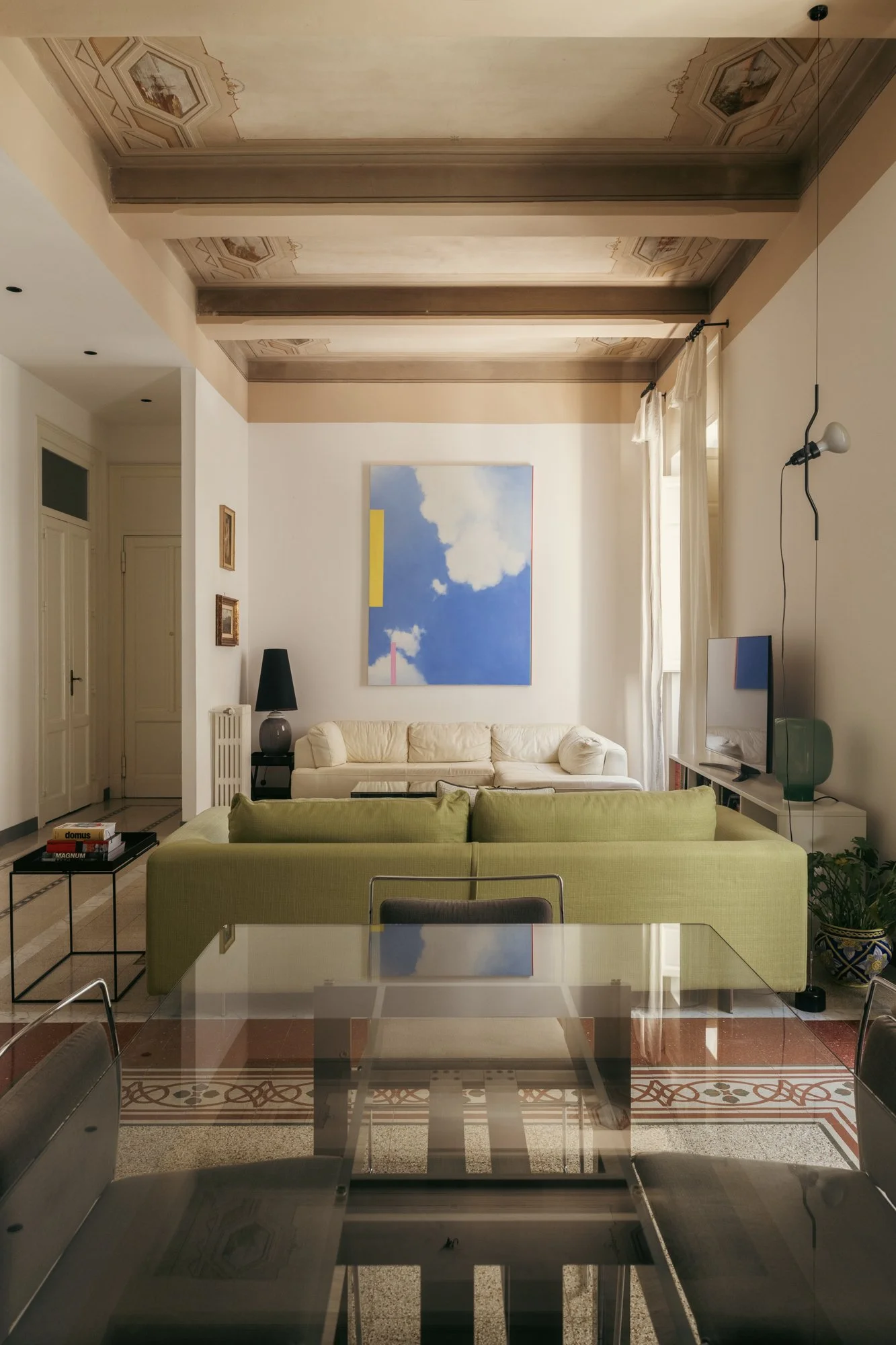 Nella zona giorno dell'appartamento storico a Palermo, il restauro dei soffitti decorati e dei pavimenti originali dialoga con arredi contemporanei, valorizzando la memoria degli ambienti.