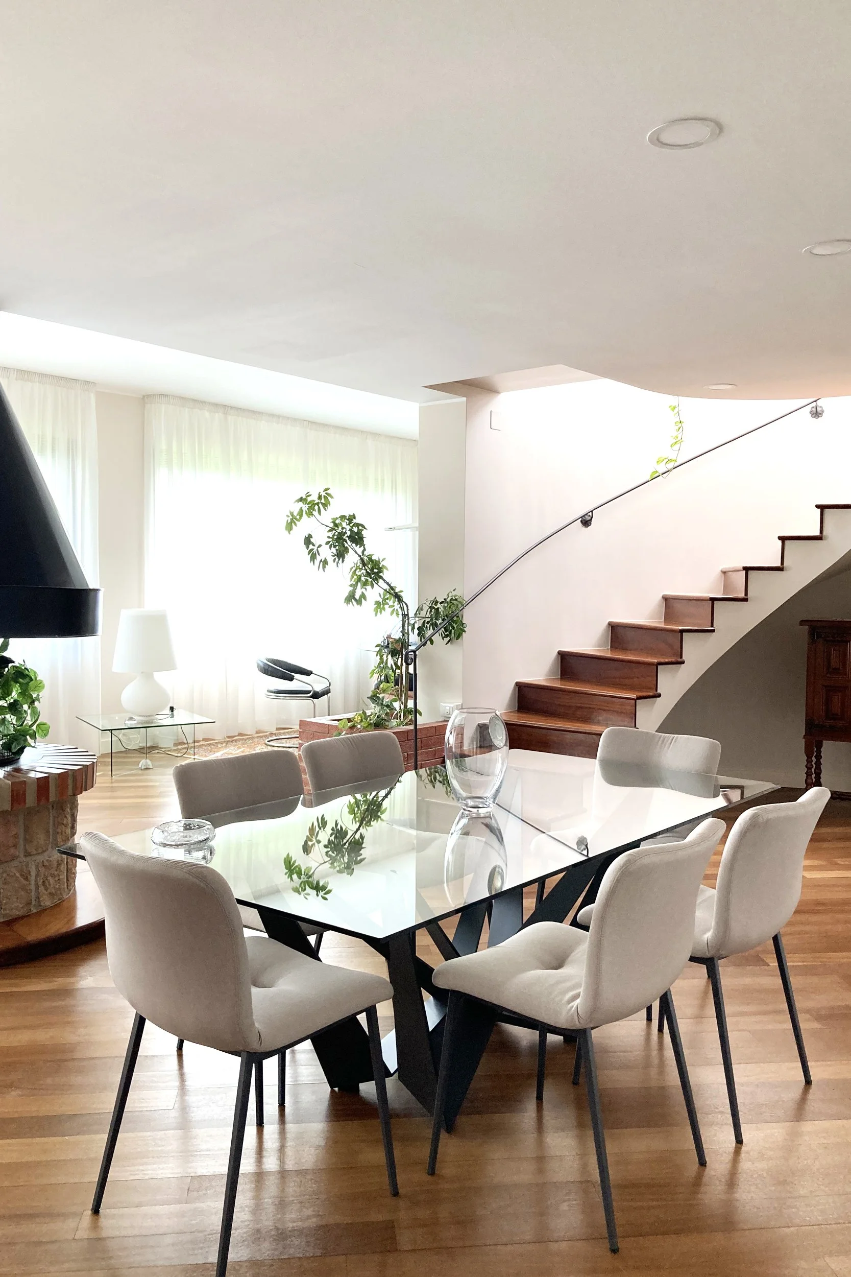 Soggiorno con scala recuperata, tavolo di design e parquet esistente in villa ristrutturata a Palermo.