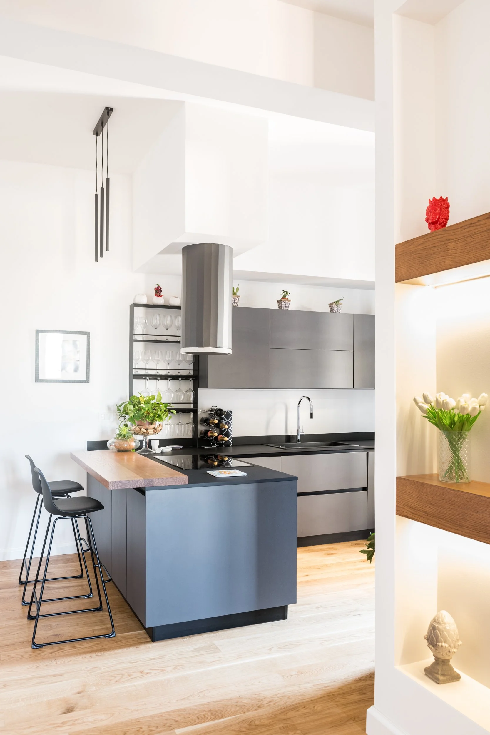 Ristrutturazione di appartamento a Palermo con cucina design a isola, volumi architettonici sospesi, falegnameria su misura illuminata e parquet in rovere naturale.