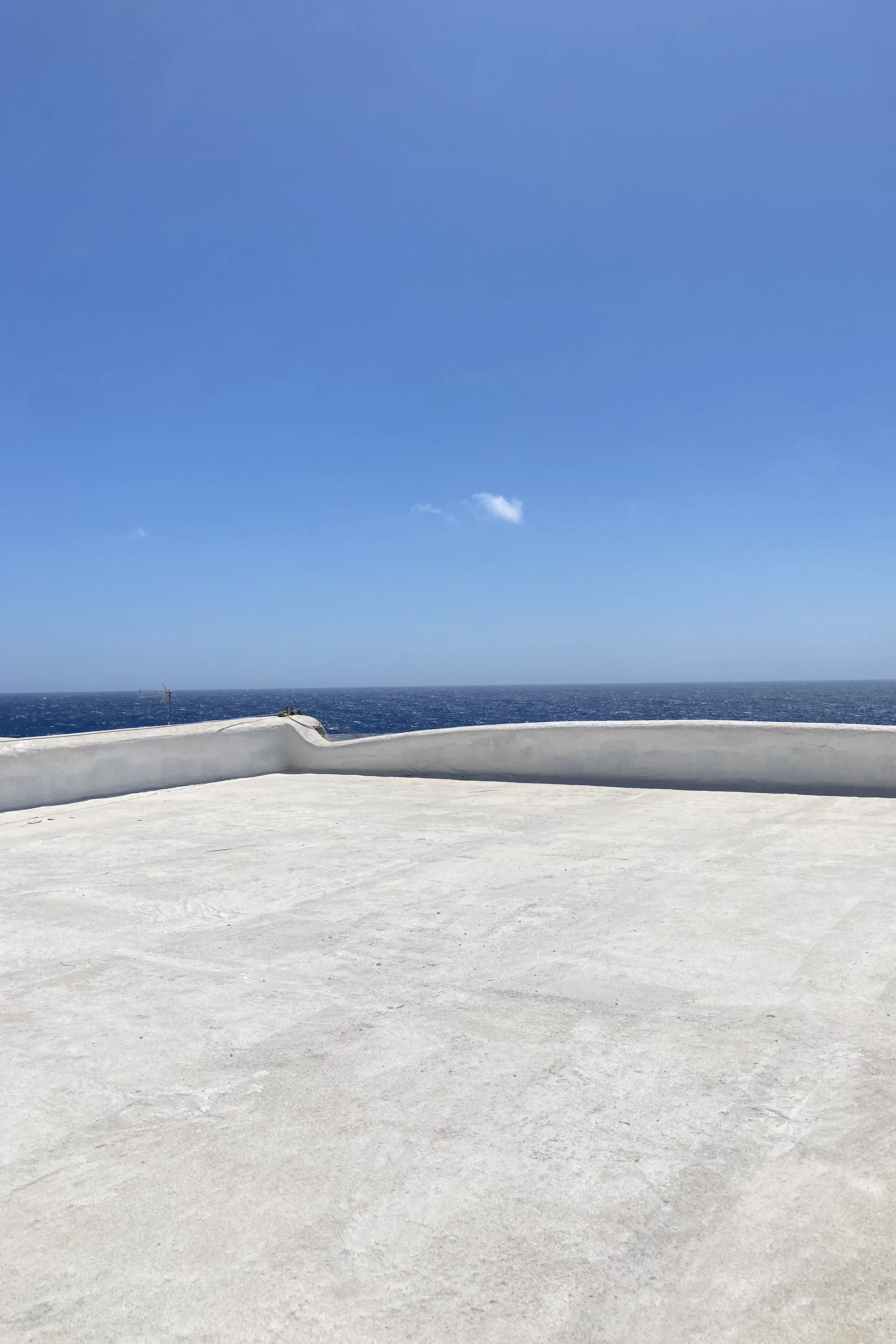 Copertura di dammuso ristrutturato a Pantelleria con parapetto curvo bianco e vista sul Mar Mediterraneo.