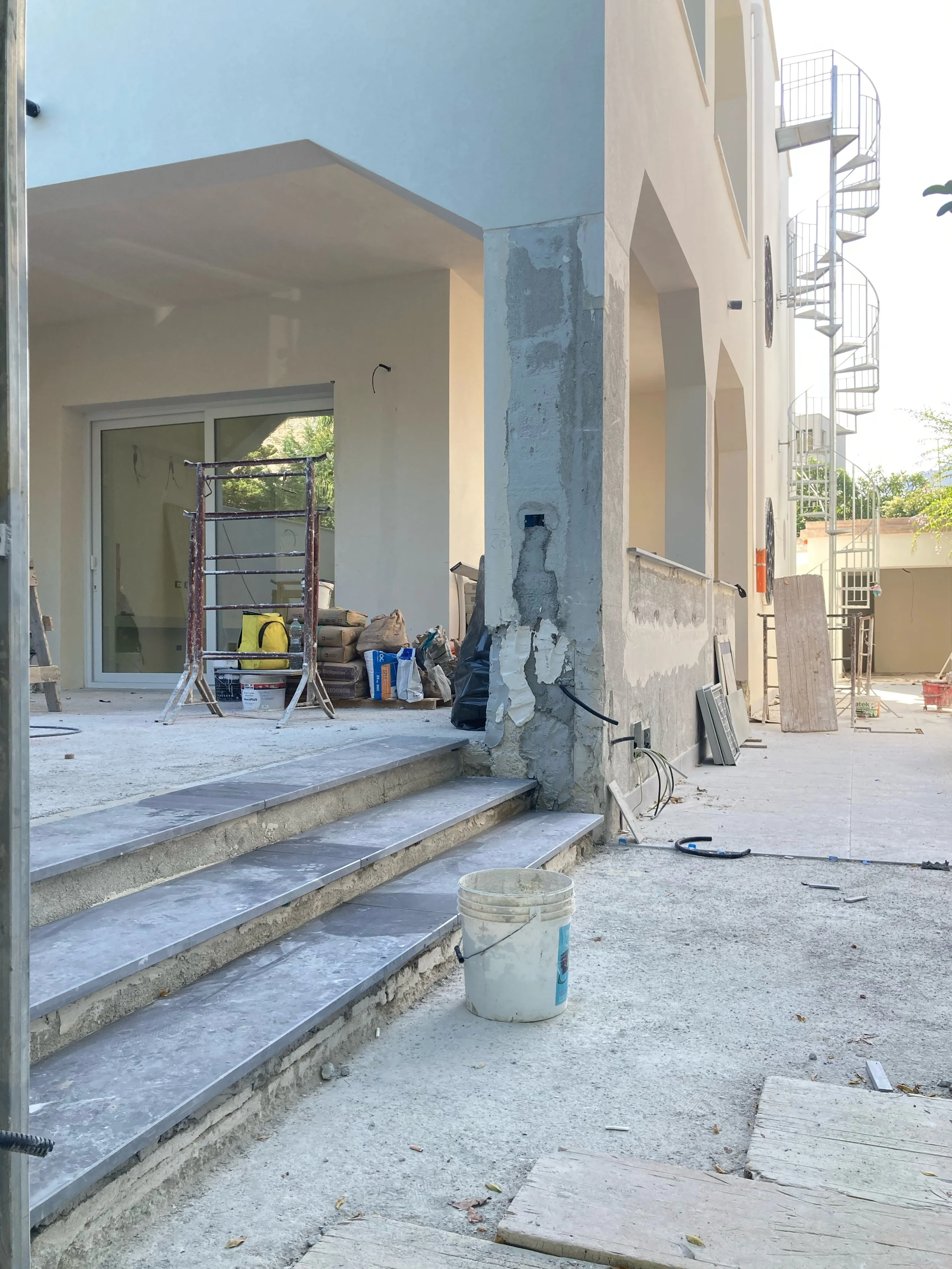 Il cantiere documenta la nuova relazione tra soggiorno, terrazza e giardino ottenuta attraverso l'uniformazione delle quote interne ed esterne. L'intervento rafforza la continuità fisica e percettiva tra gli ambienti interni e lo spazio aperto, uno d