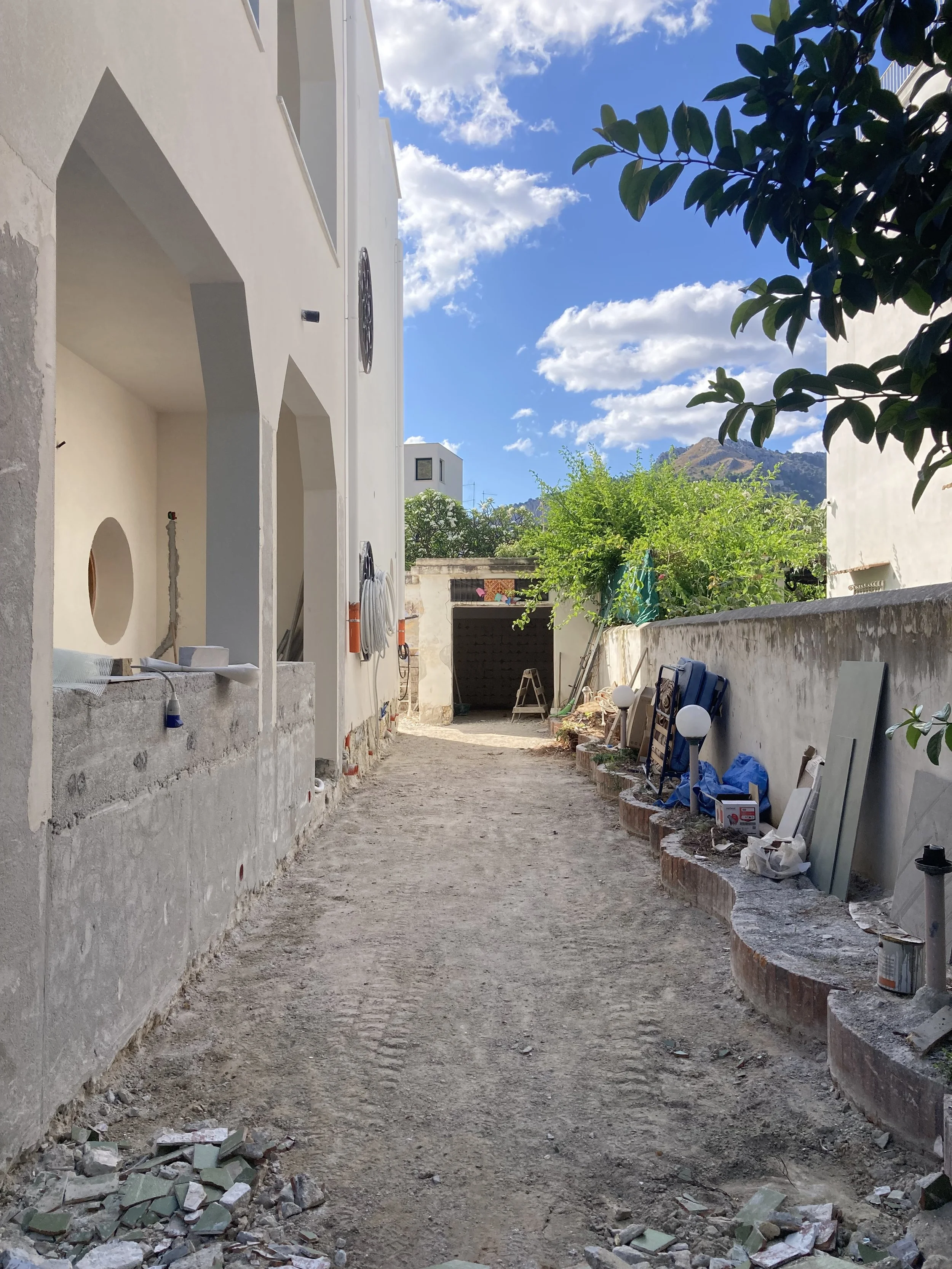 L'intervento di cantiere documenta la ridefinizione delle quote esterne e degli spazi di accesso della villa. La nuova configurazione prepara la continuità tra architettura, giardino e percorsi esterni prevista dal progetto di trasformazione in due a
