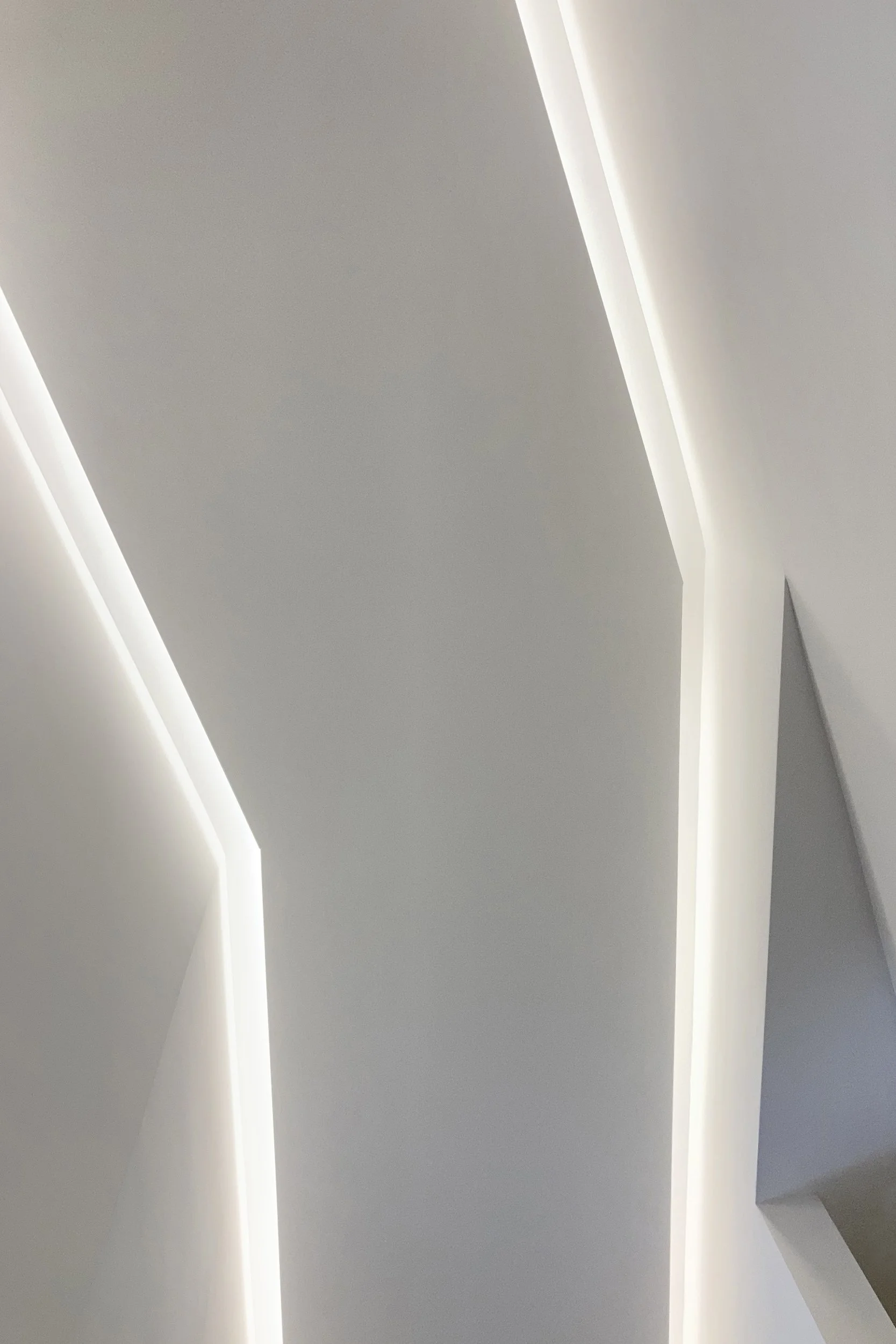 Tagli luminosi integrati nel controsoffitto e geometrie acute del corridoio nell'intervento di ristrutturazione dell'appartamento Tornasole a Palermo.