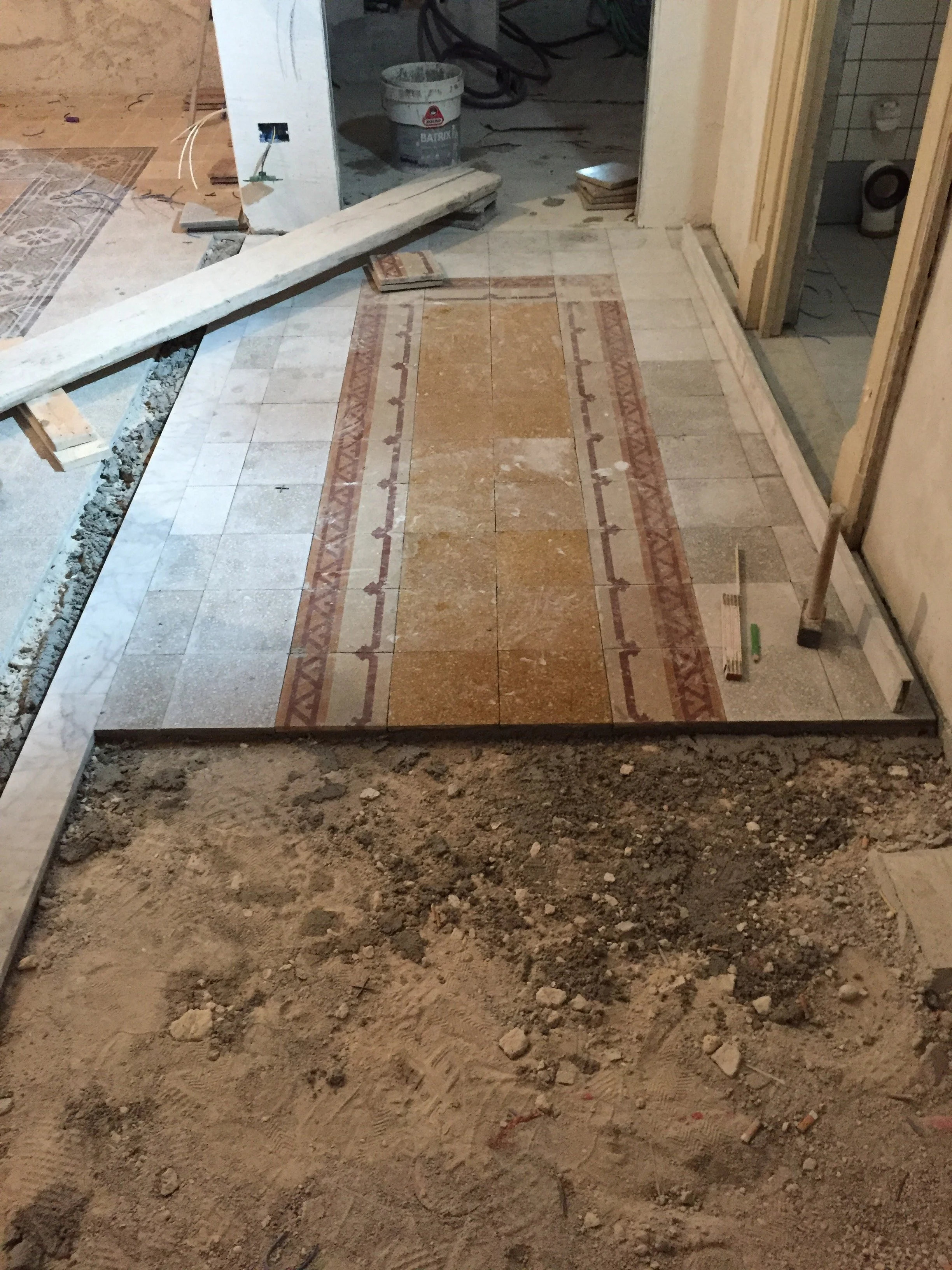 Restauro e ricomposizione di pavimento storico in cementine in un appartamento d'epoca a Palermo. L'immagine documenta il rimontaggio del tappeto originale dopo le operazioni di smontaggio necessarie alla trasformazione e al frazionamento dell'abitaz