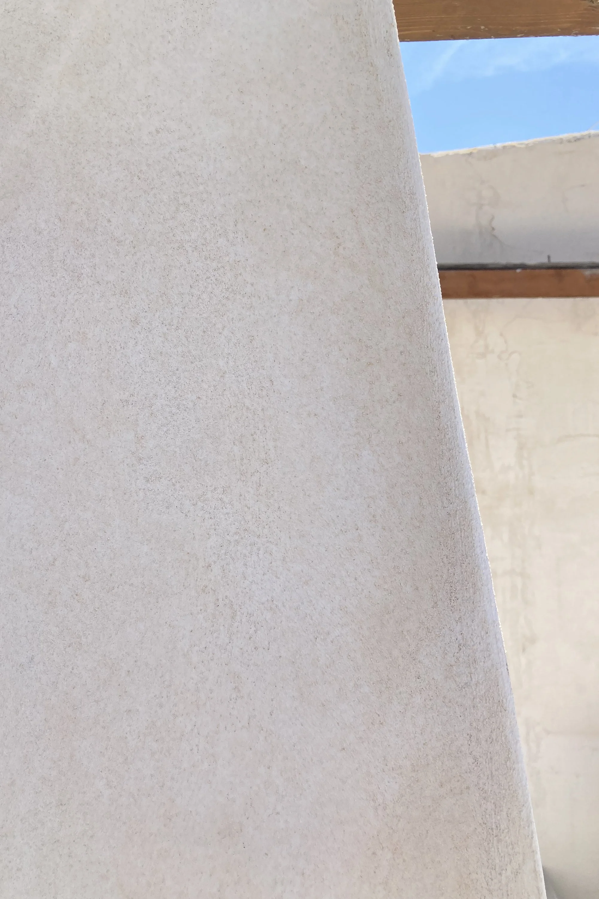 Dettaglio della massa muraria modellata nel progetto Lithos. La superficie curva interpreta la tradizione costruttiva del dammuso pantesco trasformando la materia in elemento generatore dello spazio. La luce mediterranea evidenzia la continuità delle